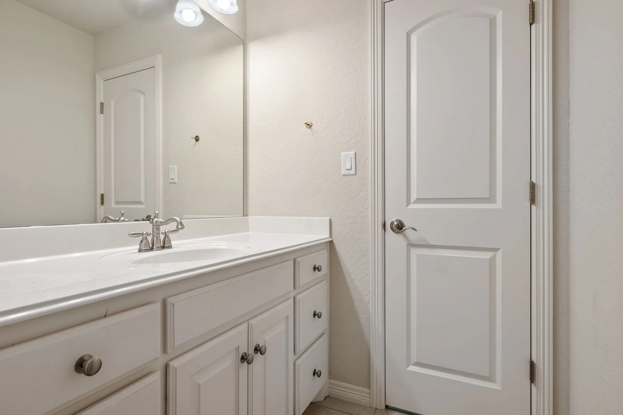Vanity featuring an integrated sink, brushed nickel faucet, and white cabinetry with coordinating hardware