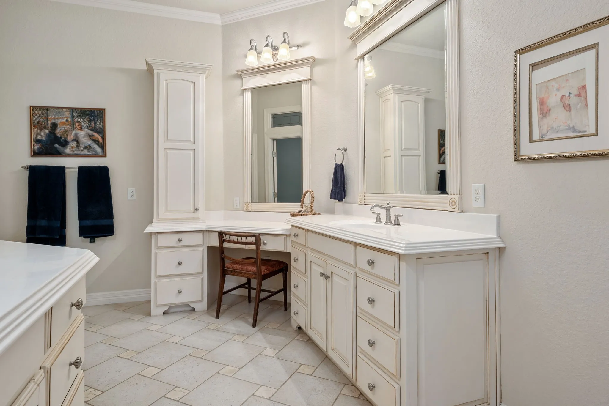 Dual vanity with integrated sink, white cabinetry, built-in storage tower, and a vanity area