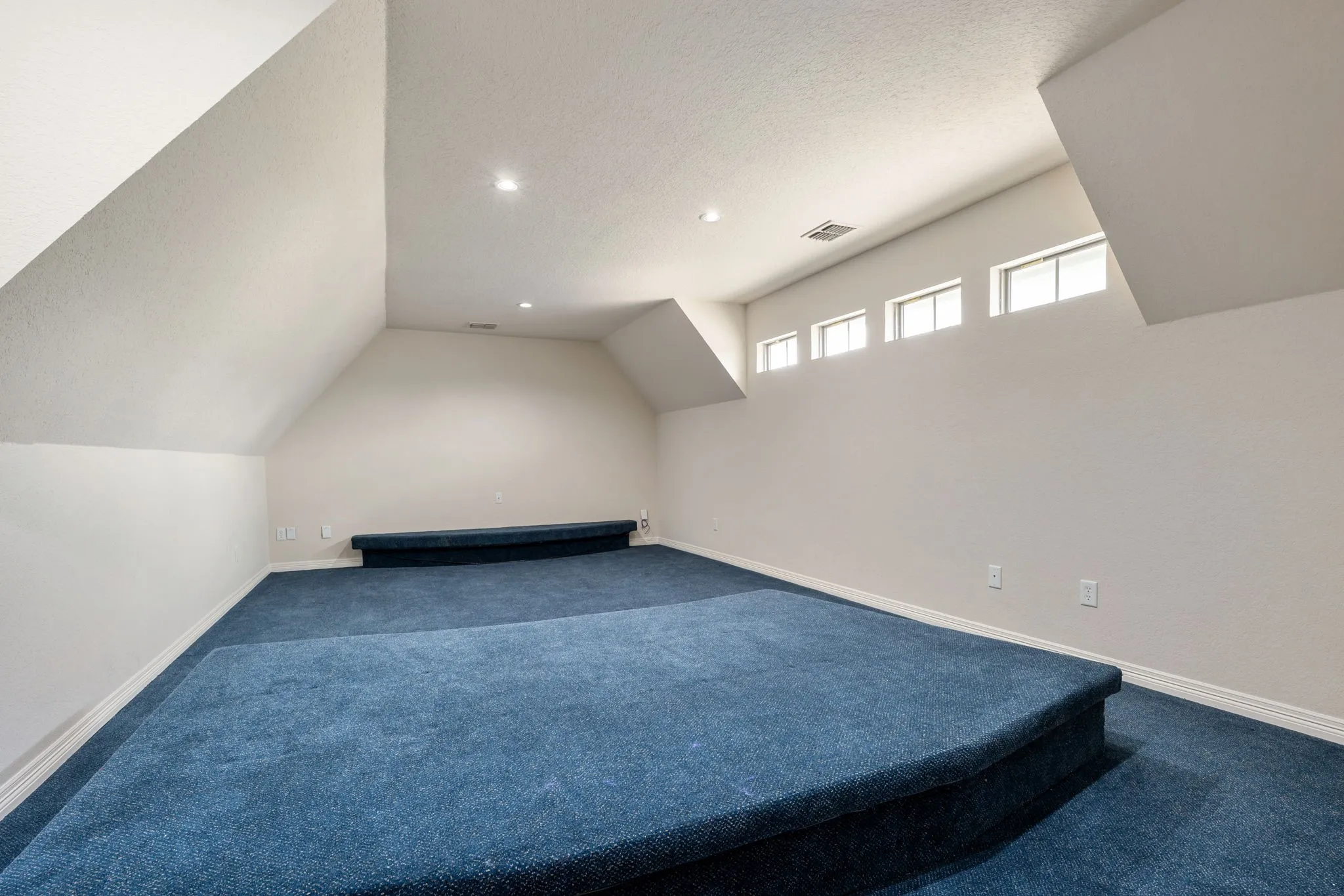 Tiered blue carpeting and recessed lighting