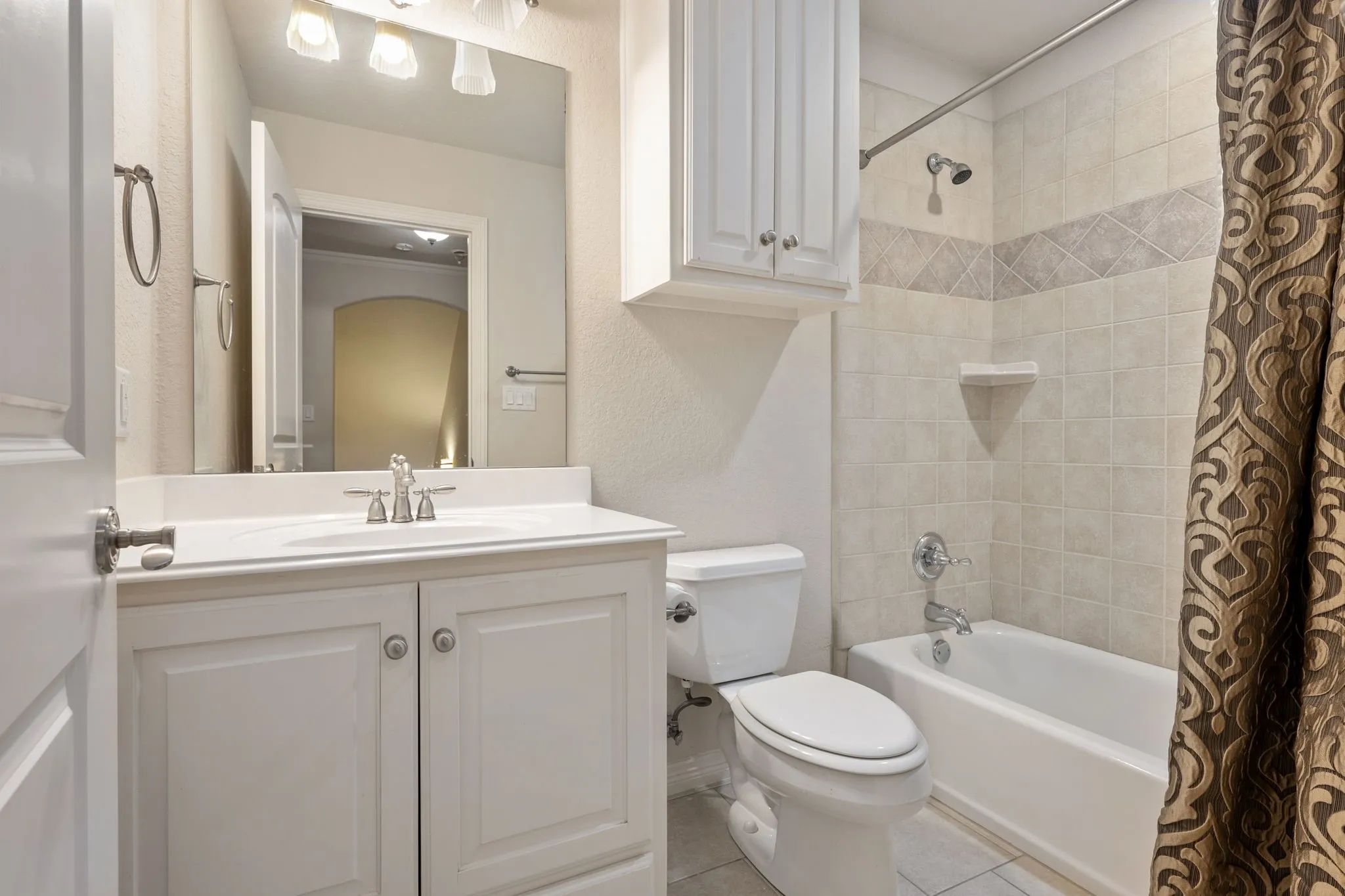 Bathroom featuring a vanity with white cabinetry, a built-in sink, and brushed nickel fixtures