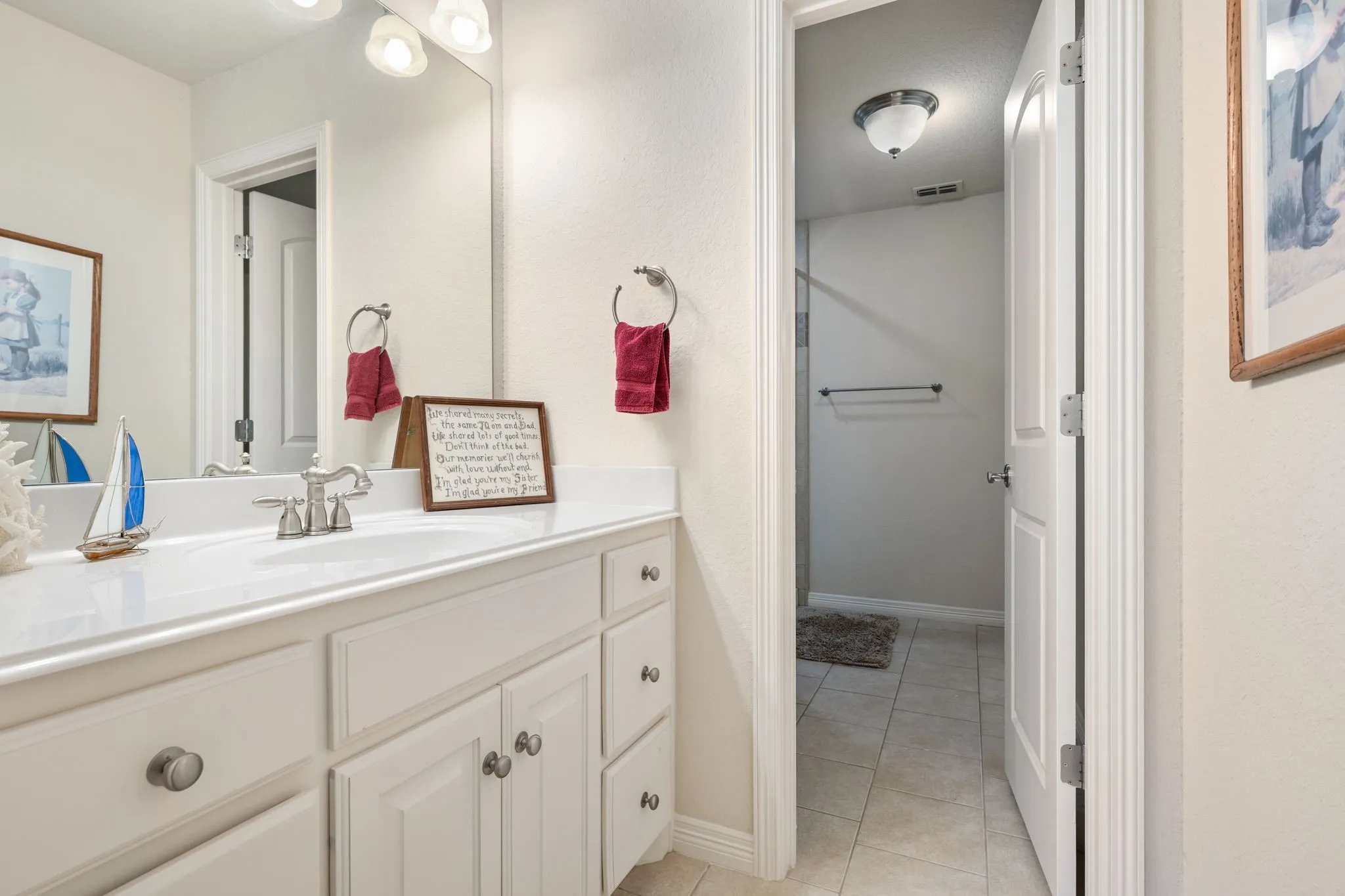 White vanity with integrated sink, brushed nickel faucet, and a wall-mounted mirror