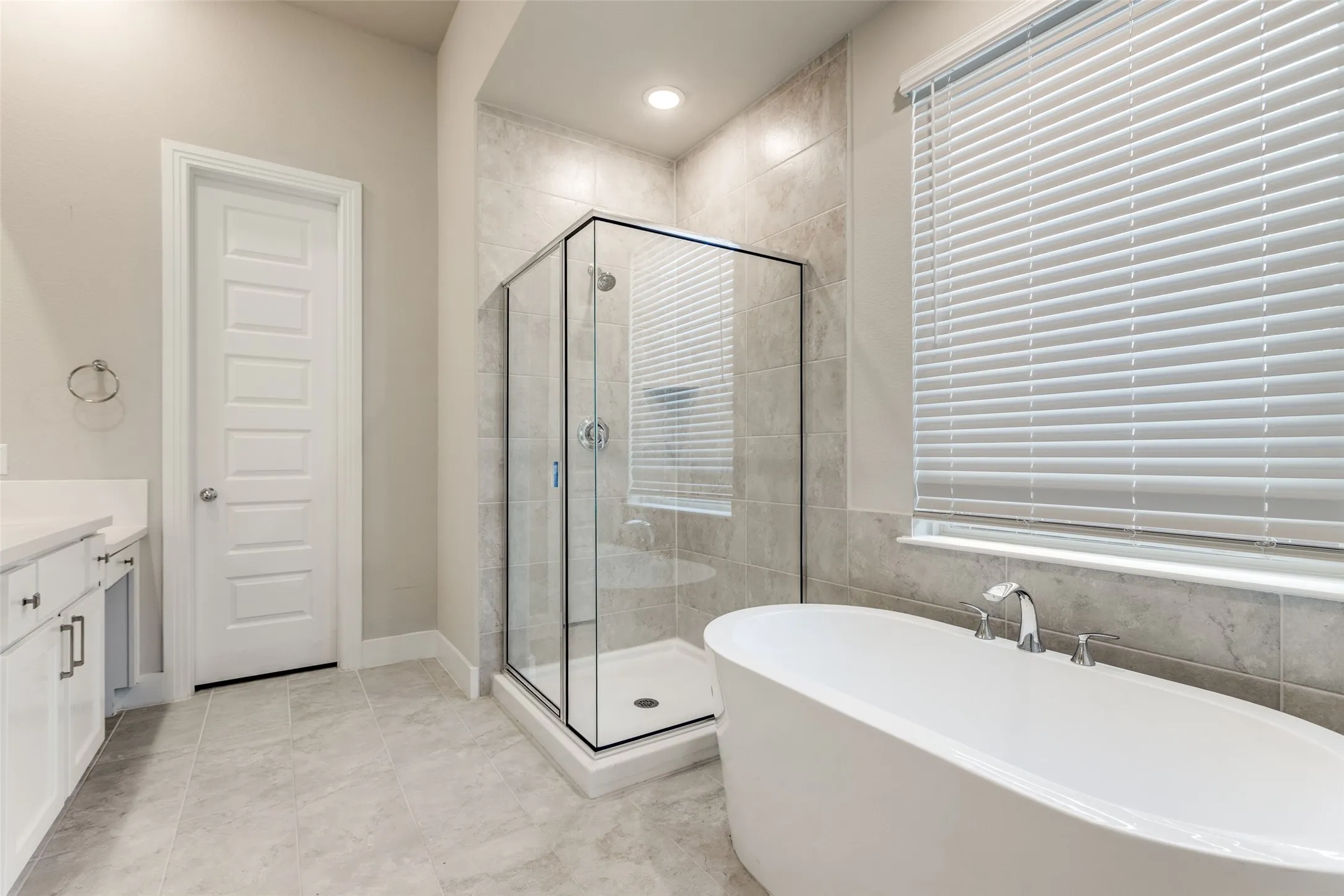 Bathroom featuring vanity, a freestanding bath, a shower stall, and light tile patterned floors