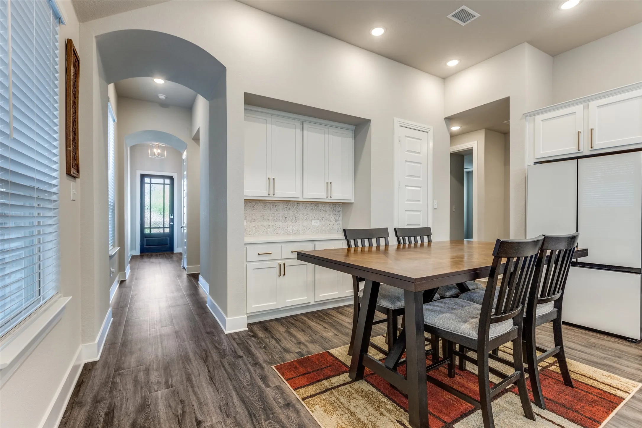 Dining area with dark wood-style flooring, arched walkways, and recessed lighting