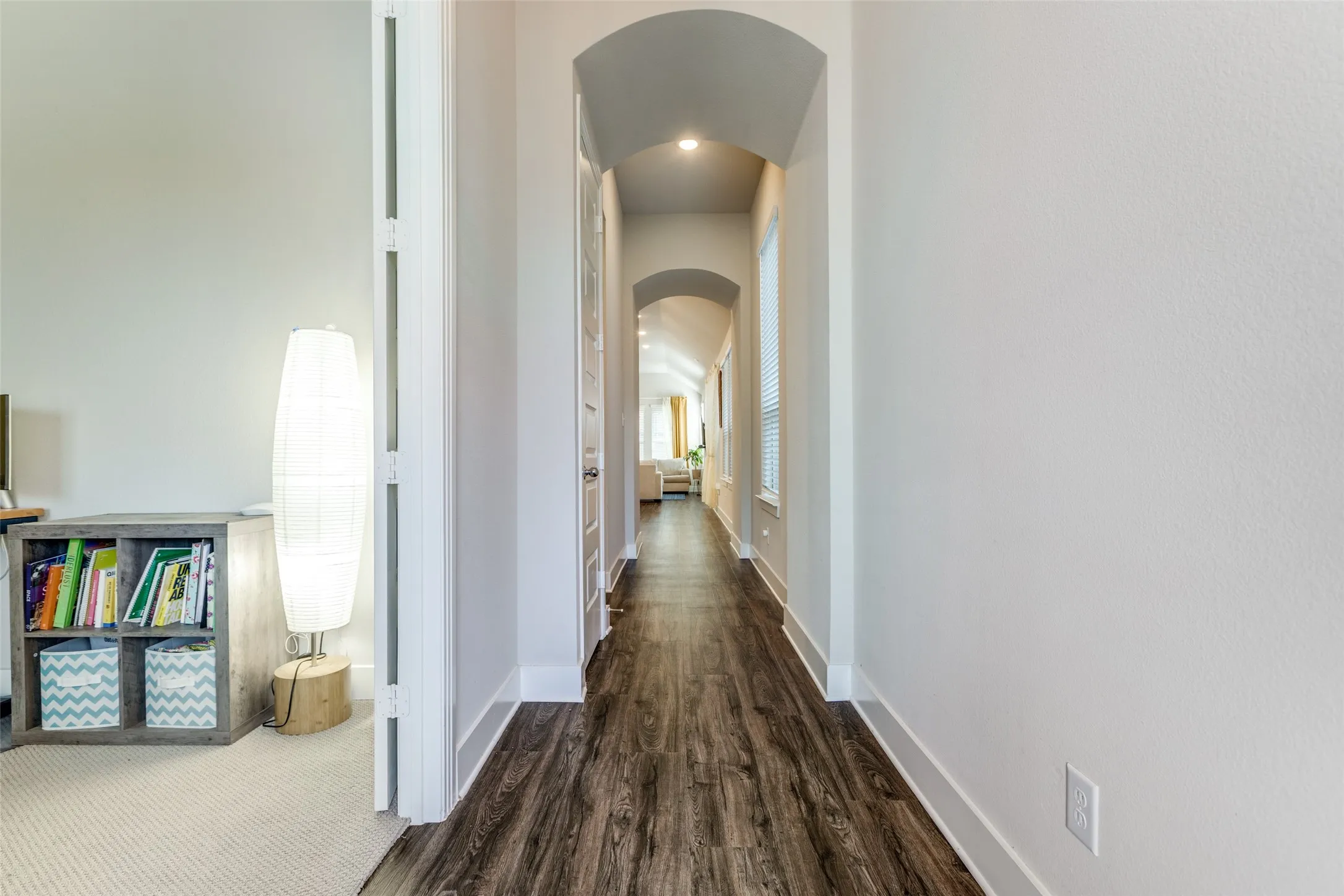 Hall with arched walkways and dark wood-type flooring