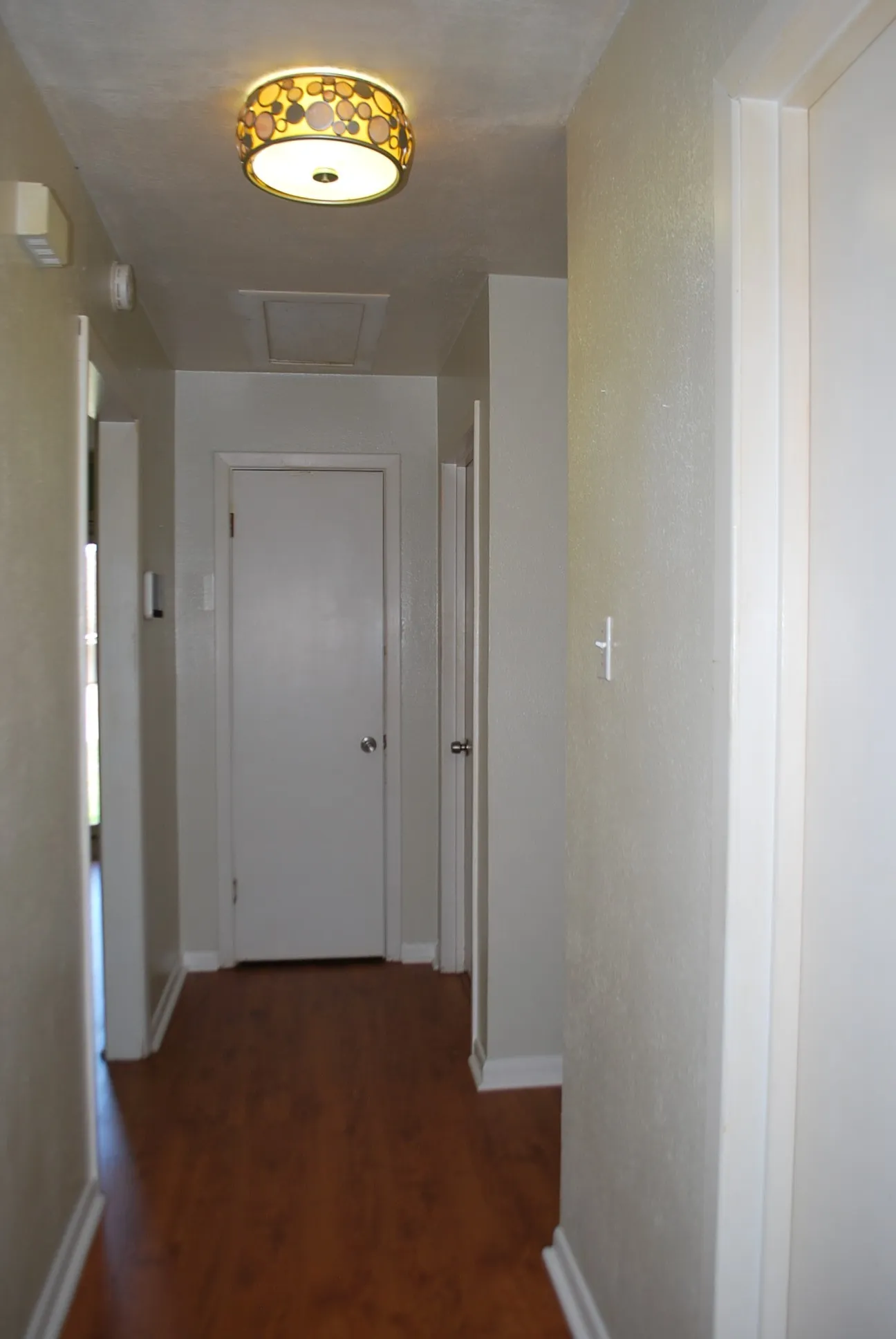 Wood-finish flooring with white trim, featuring a flush-mount ceiling light fixture