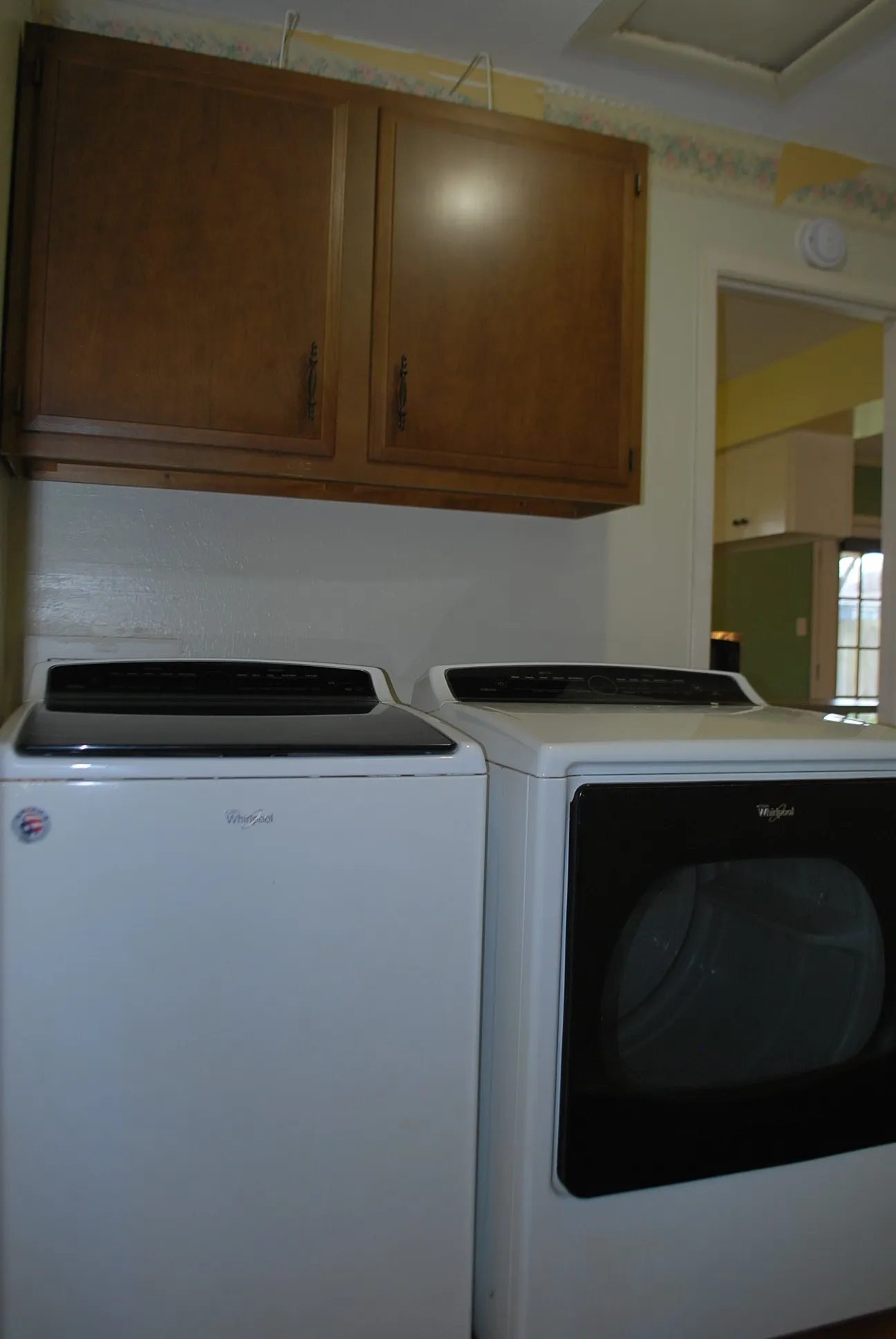 Laundry area with overhead wood-finish cabinetry