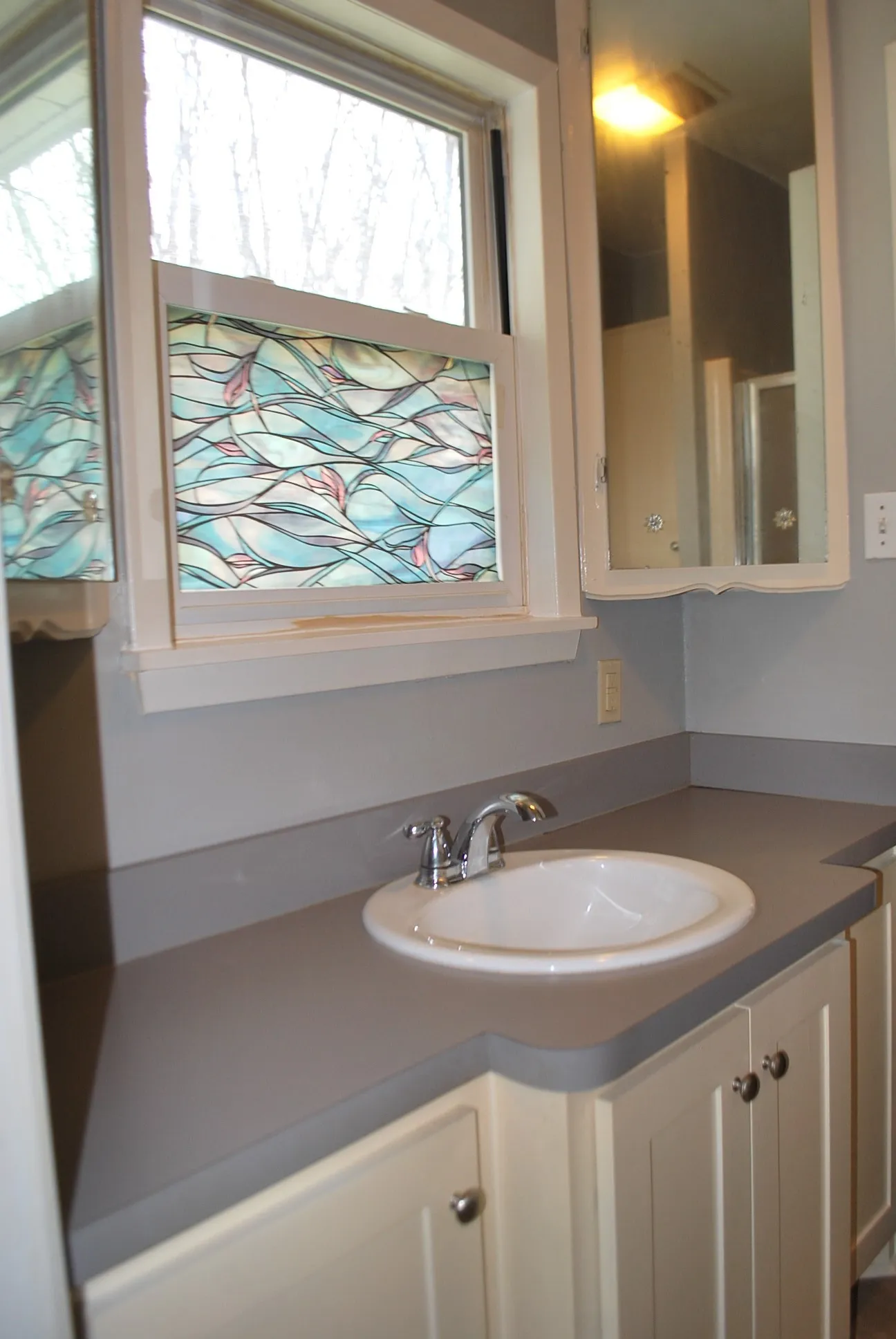 White shaker-style cabinetry with chrome hardware, an integrated basin sink, and a gray countertop