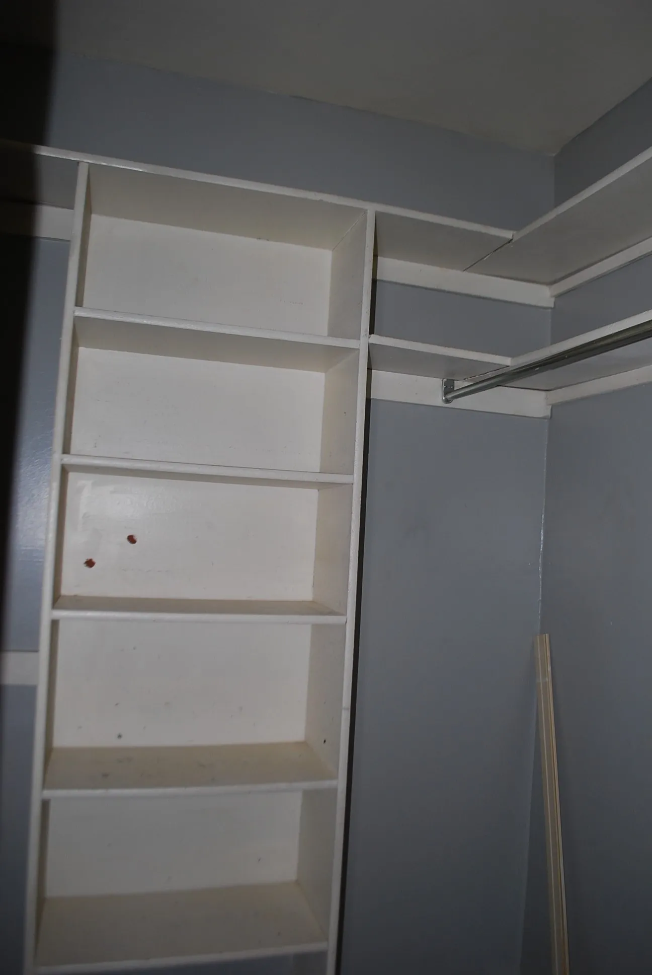Built-in shelving with multiple storage compartments and an integrated hanging rod