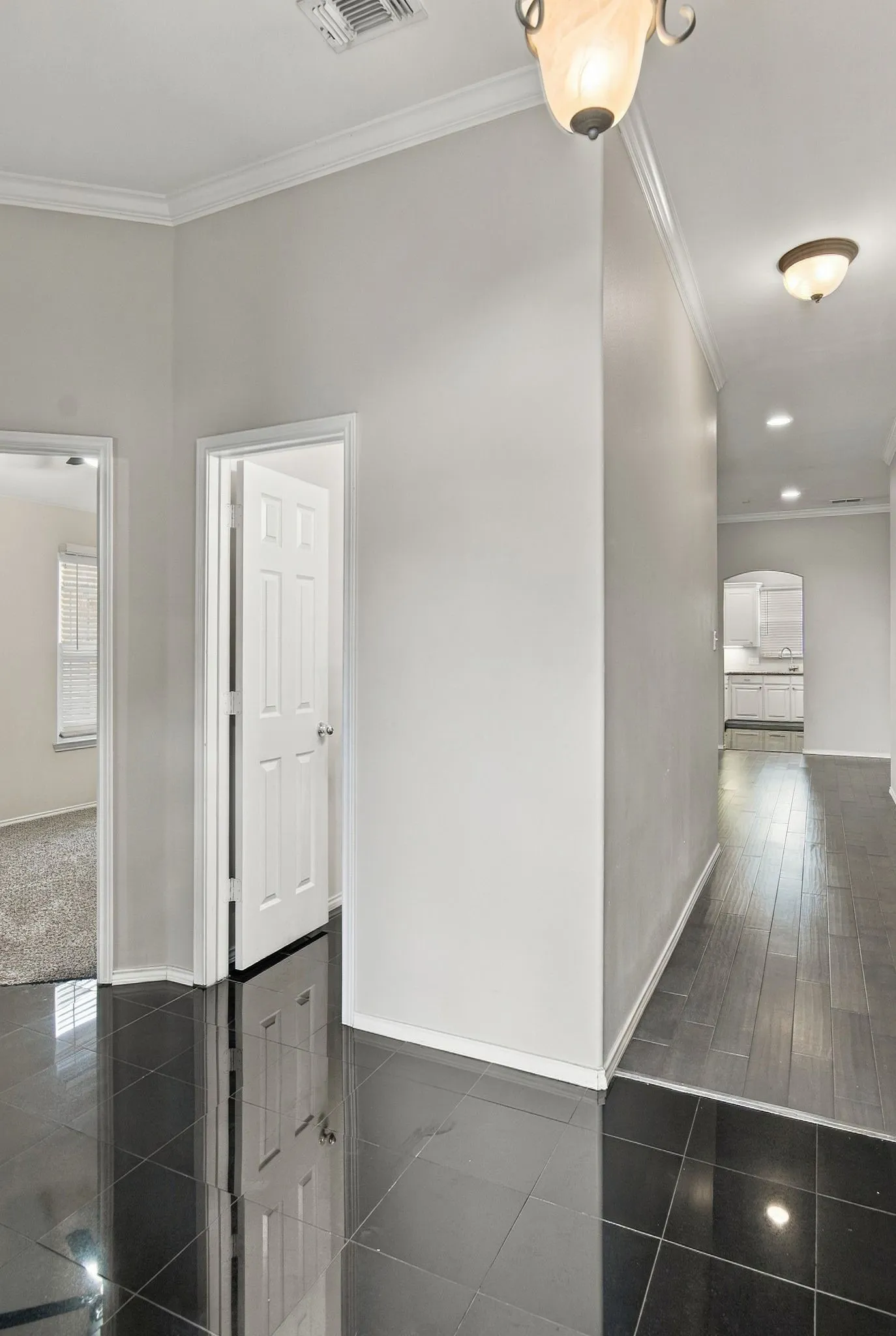Black tile flooring, crown molding, wood-finish flooring, recessed lighting, arched doorway