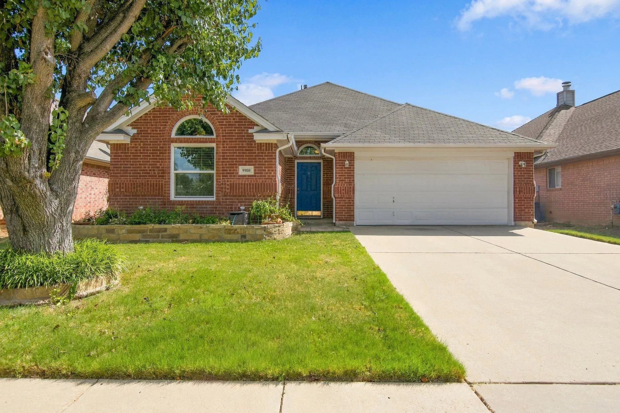 Brick exterior with a prominent arched window, a two-car garage, and a concrete driveway