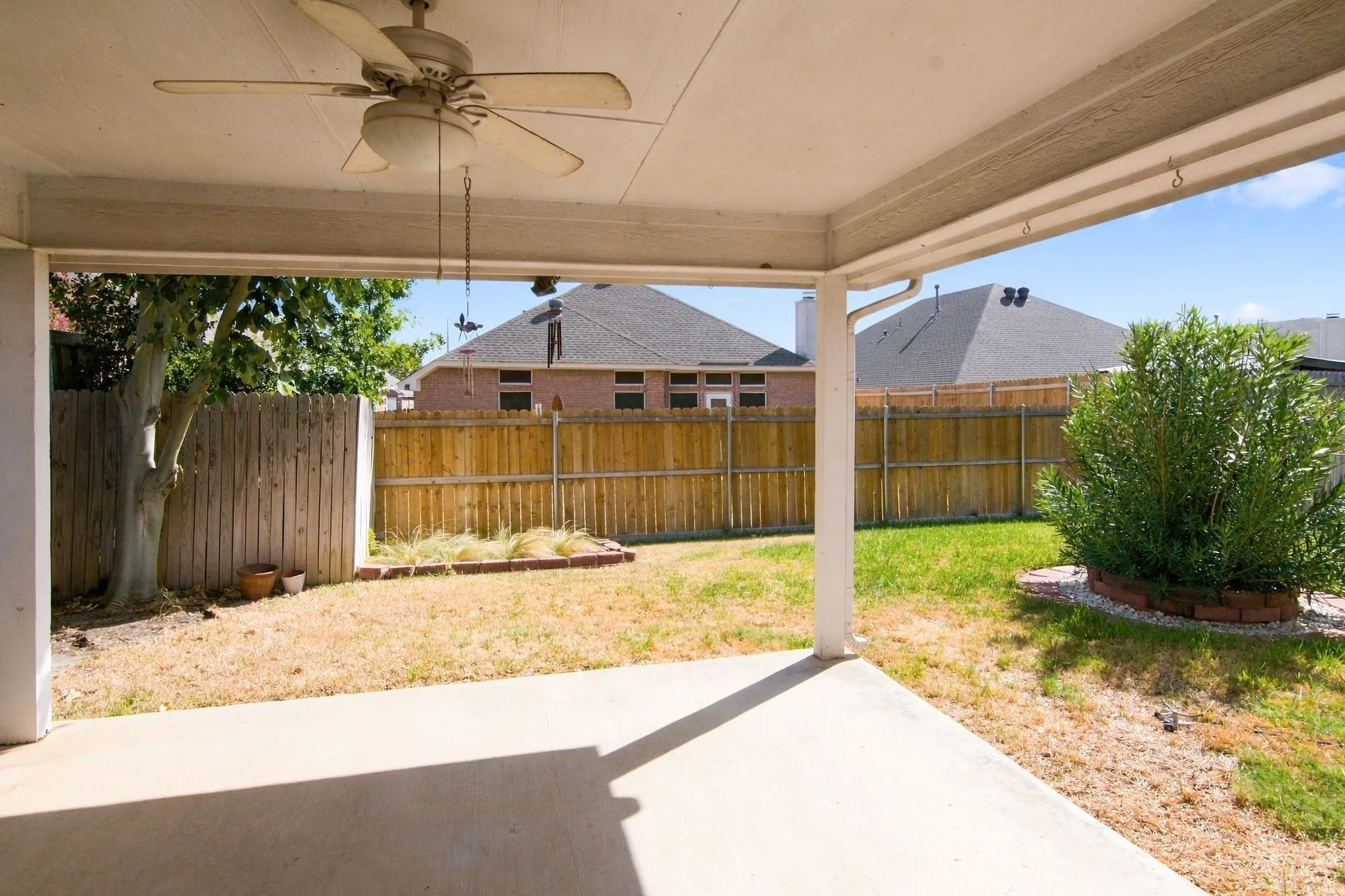 Large Covered patio with a ceiling fan, concrete deck and a private wooden fence
