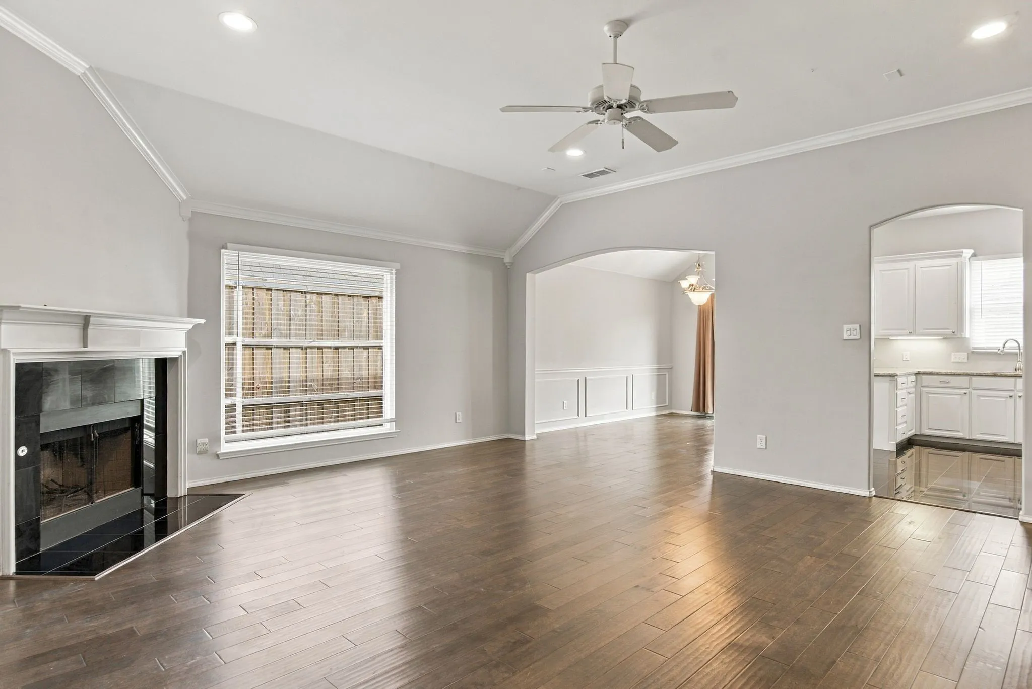 Vaulted ceiling, wood-finish flooring, fireplace with white mantel, recessed lighting, and a ceiling fan