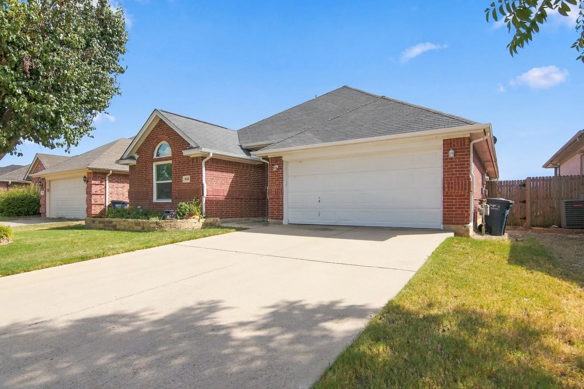 Brick exterior with arched window, concrete driveway, and attached garage