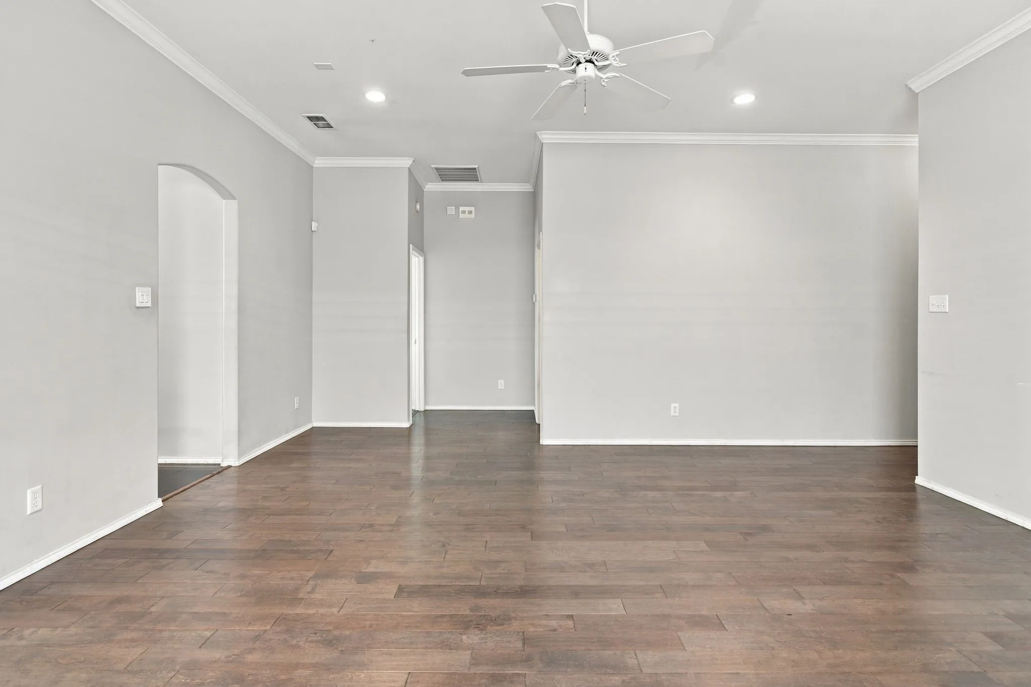 Expansive room featuring wood-finish flooring, crown molding, a ceiling fan, and recessed lighting