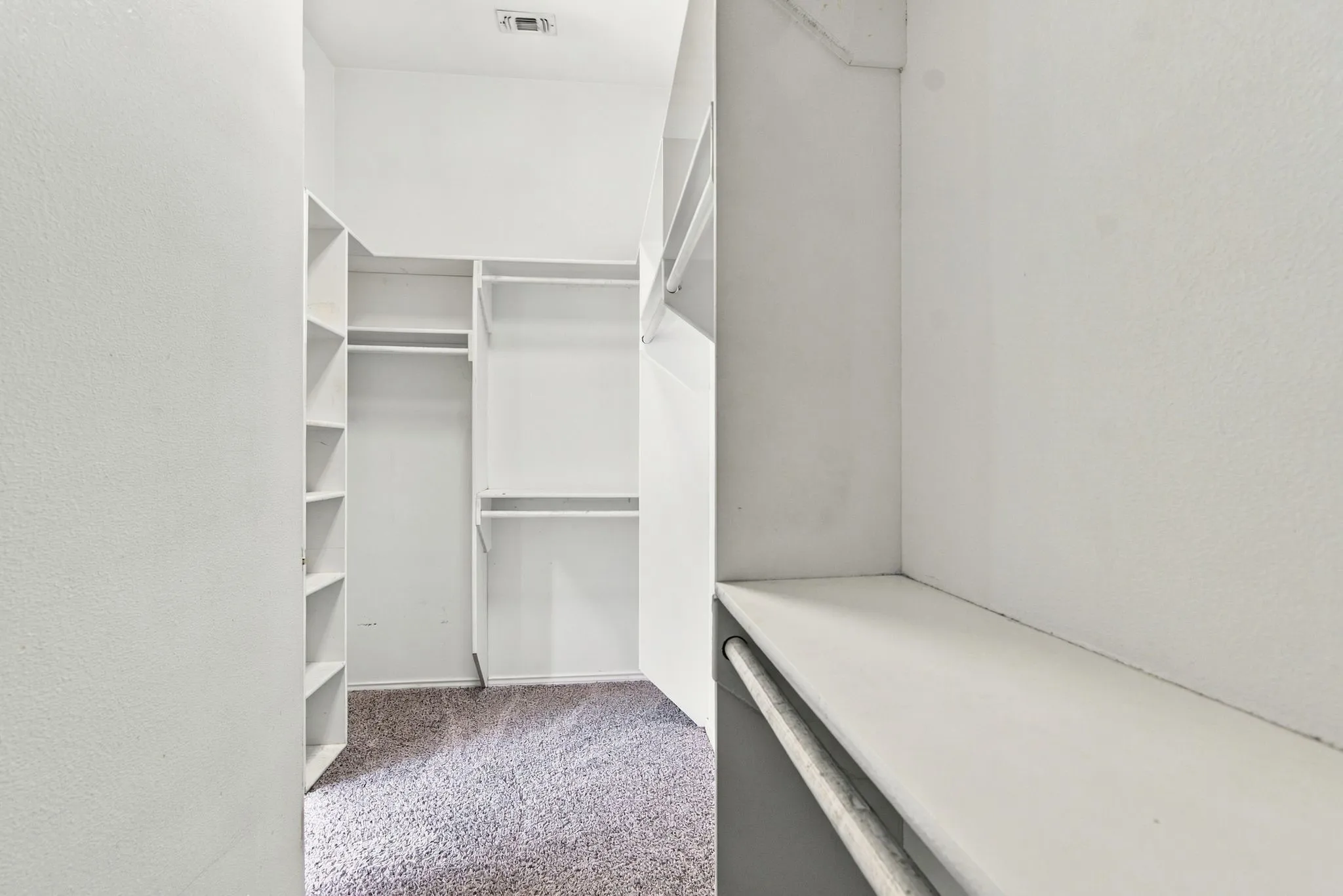 Spacious, roomy, master closet featuring  built-in shelving and multiple clothing rods