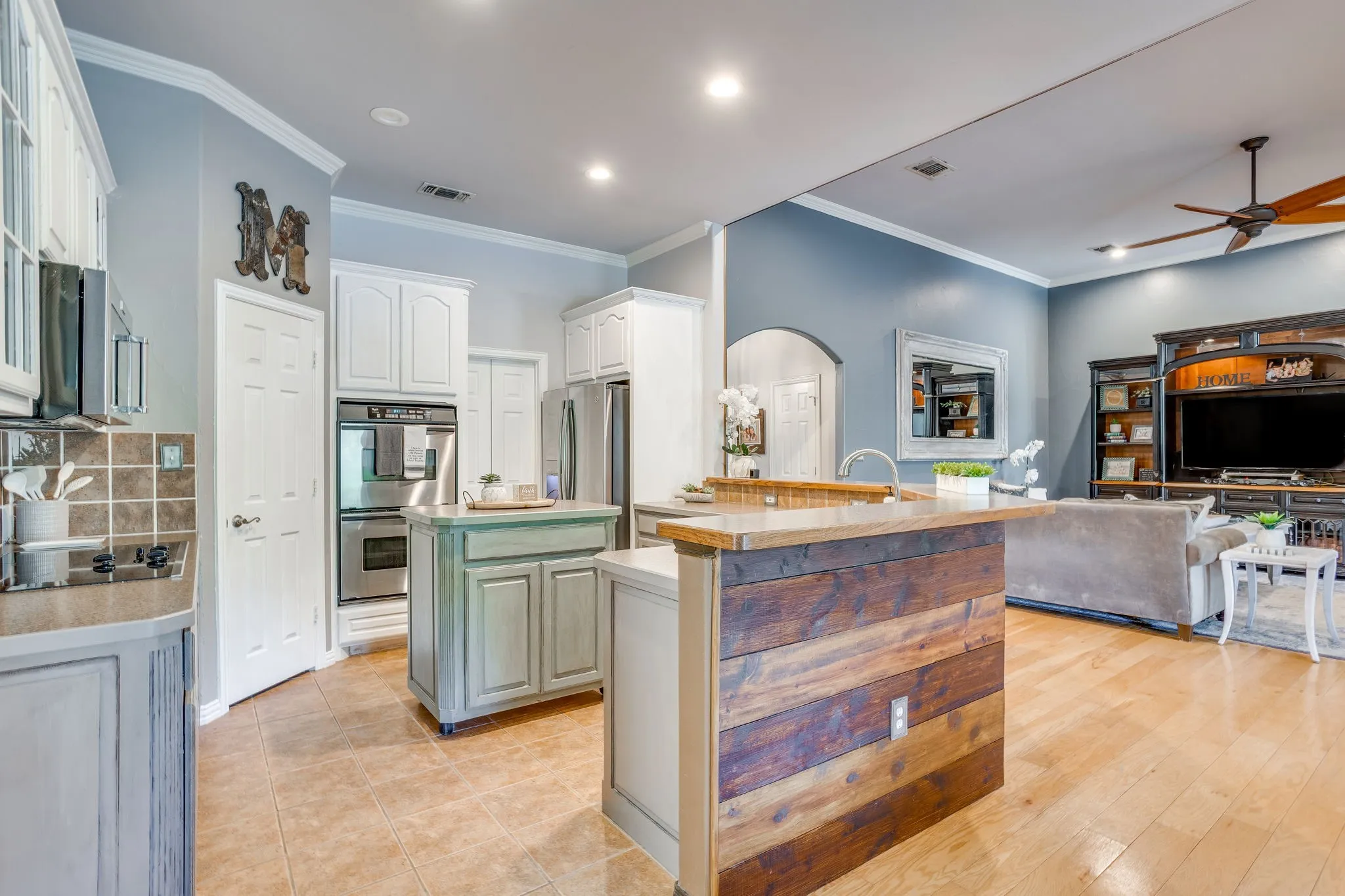 Kitchen featuring white cabinetry, stainless steel double oven, tile flooring, and a center island with a wood-finish top