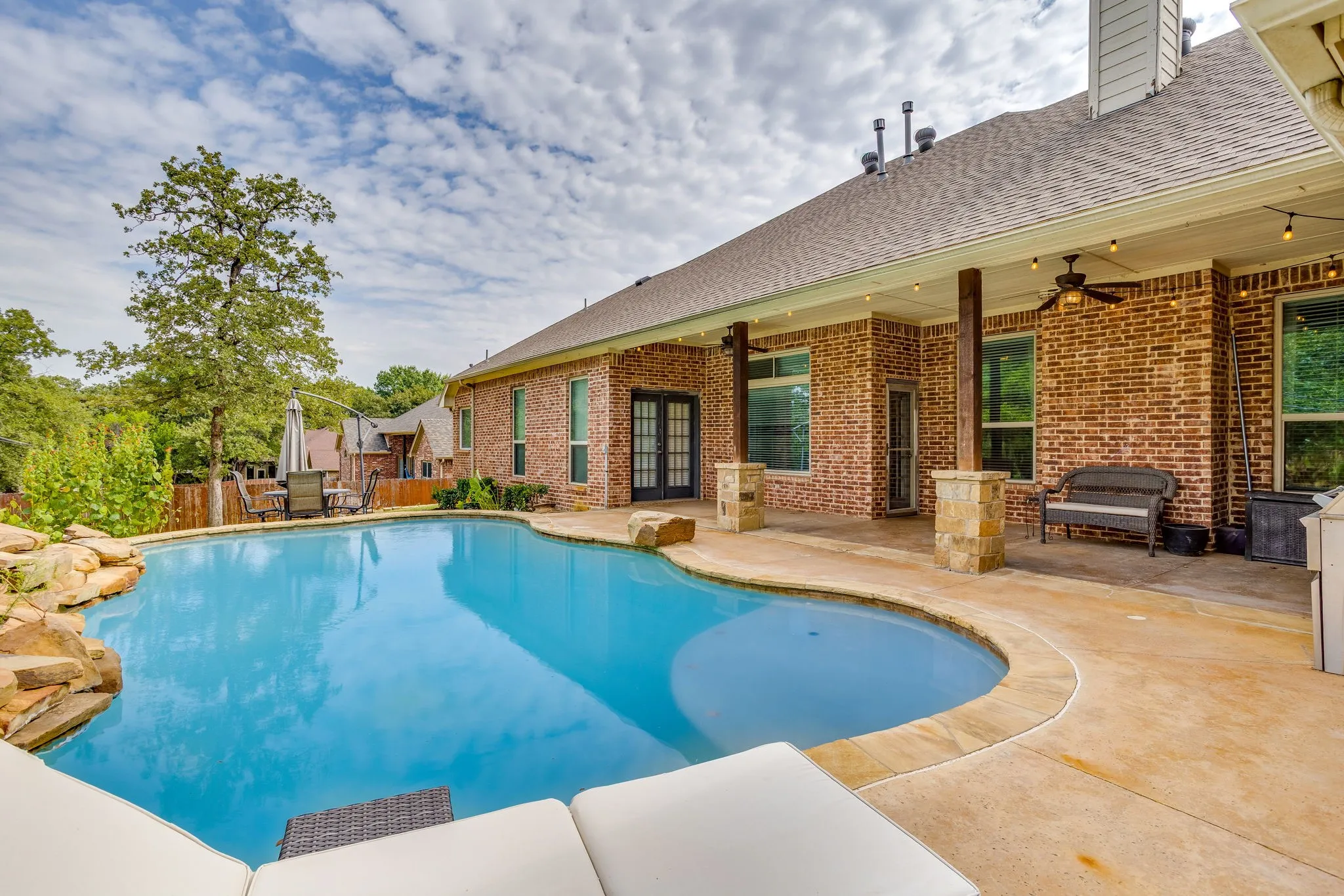 Resort-style pool with rock features and an expansive concrete patio