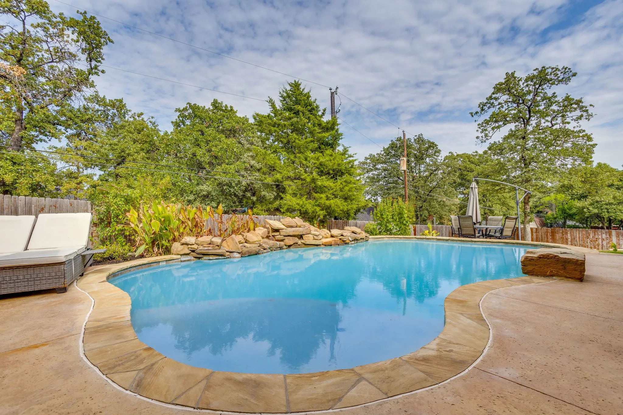 Freeform swimming pool with natural stone coping and rock waterfall feature