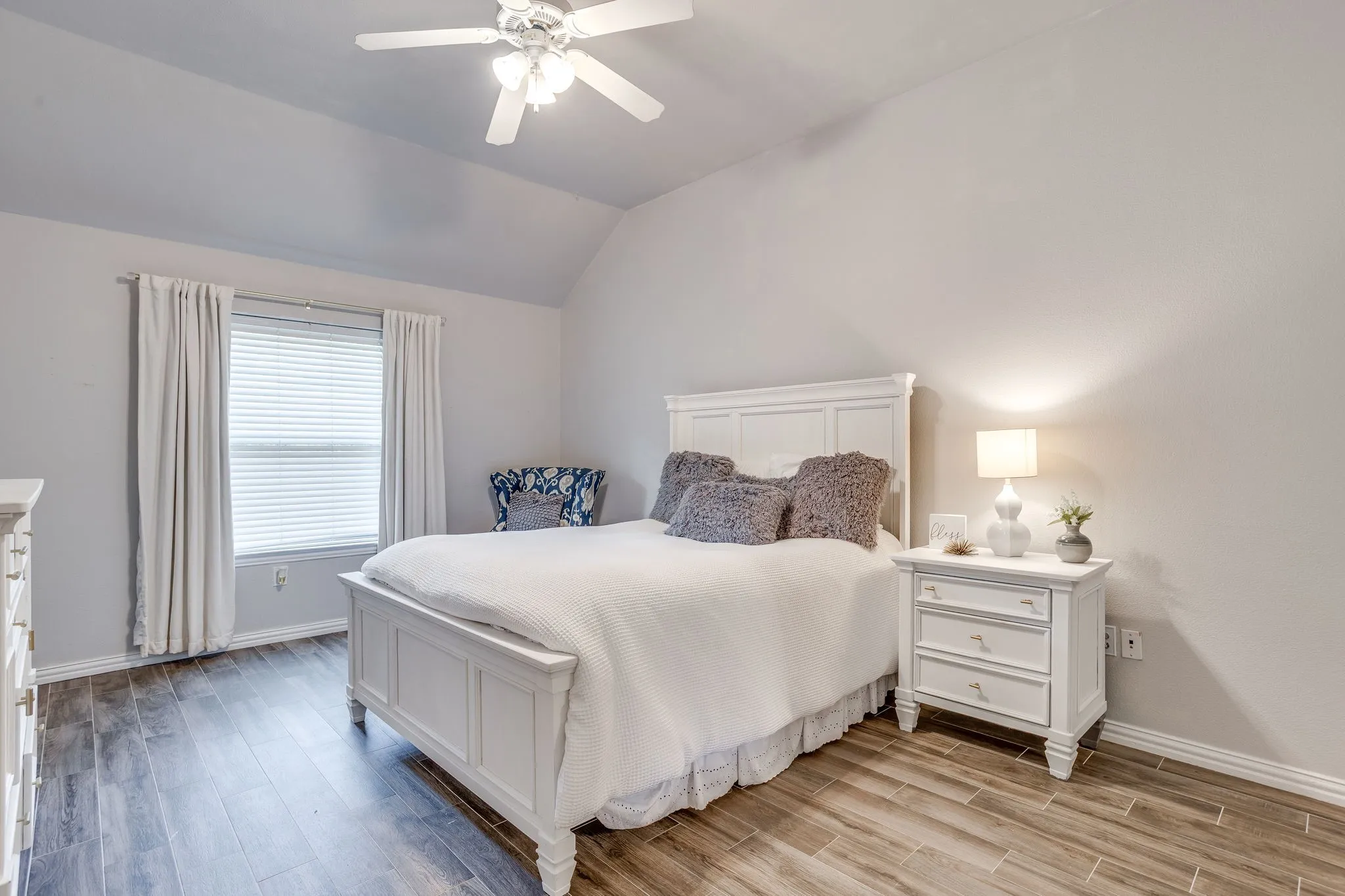 Bedroom 3 with vaulted ceiling, wood-finish flooring, white window blinds, and a ceiling fan with integrated lighting