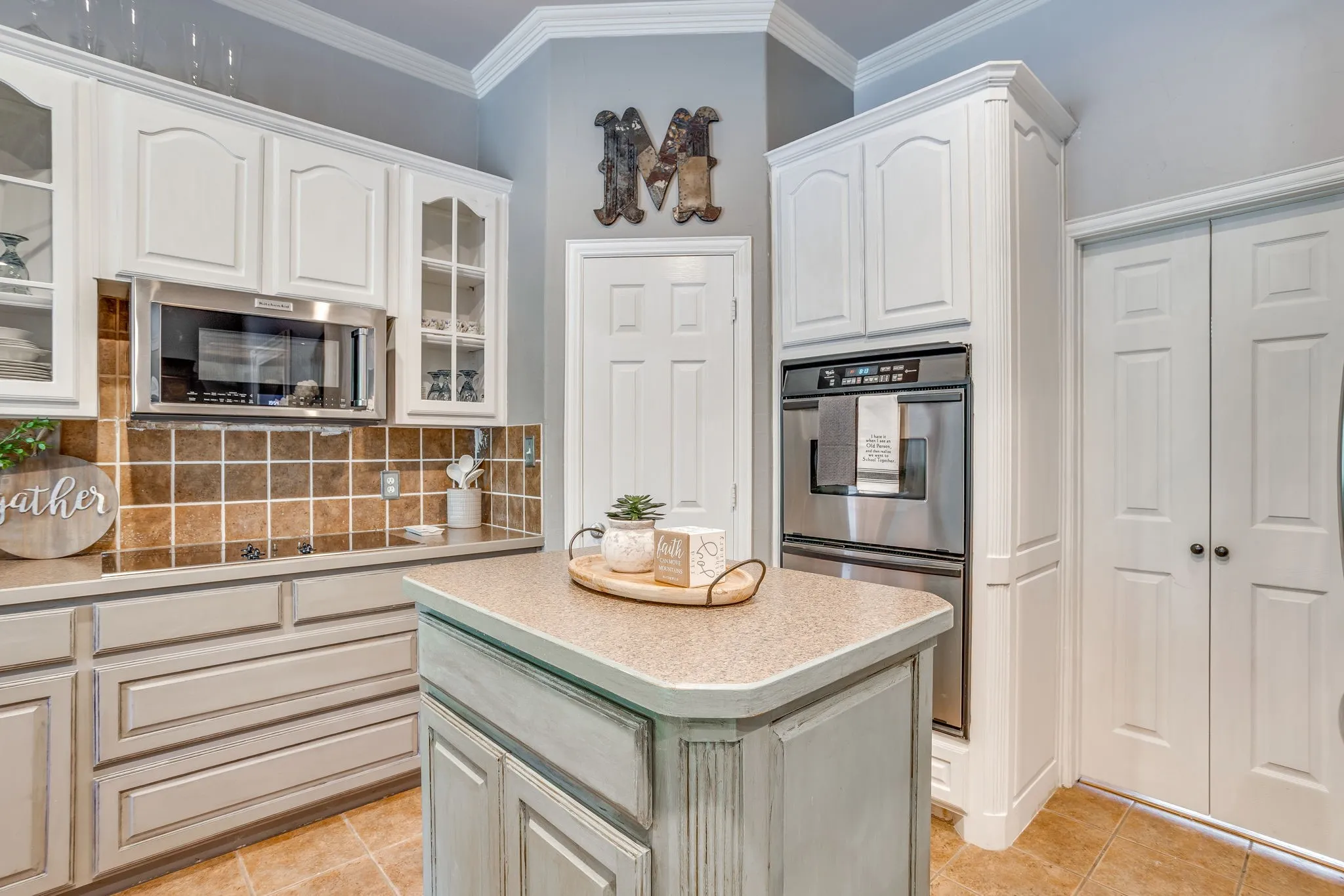 Kitchen featuring white cabinetry, a built-in microwave, stainless steel double ovens, a tiled backsplash, and a central island
