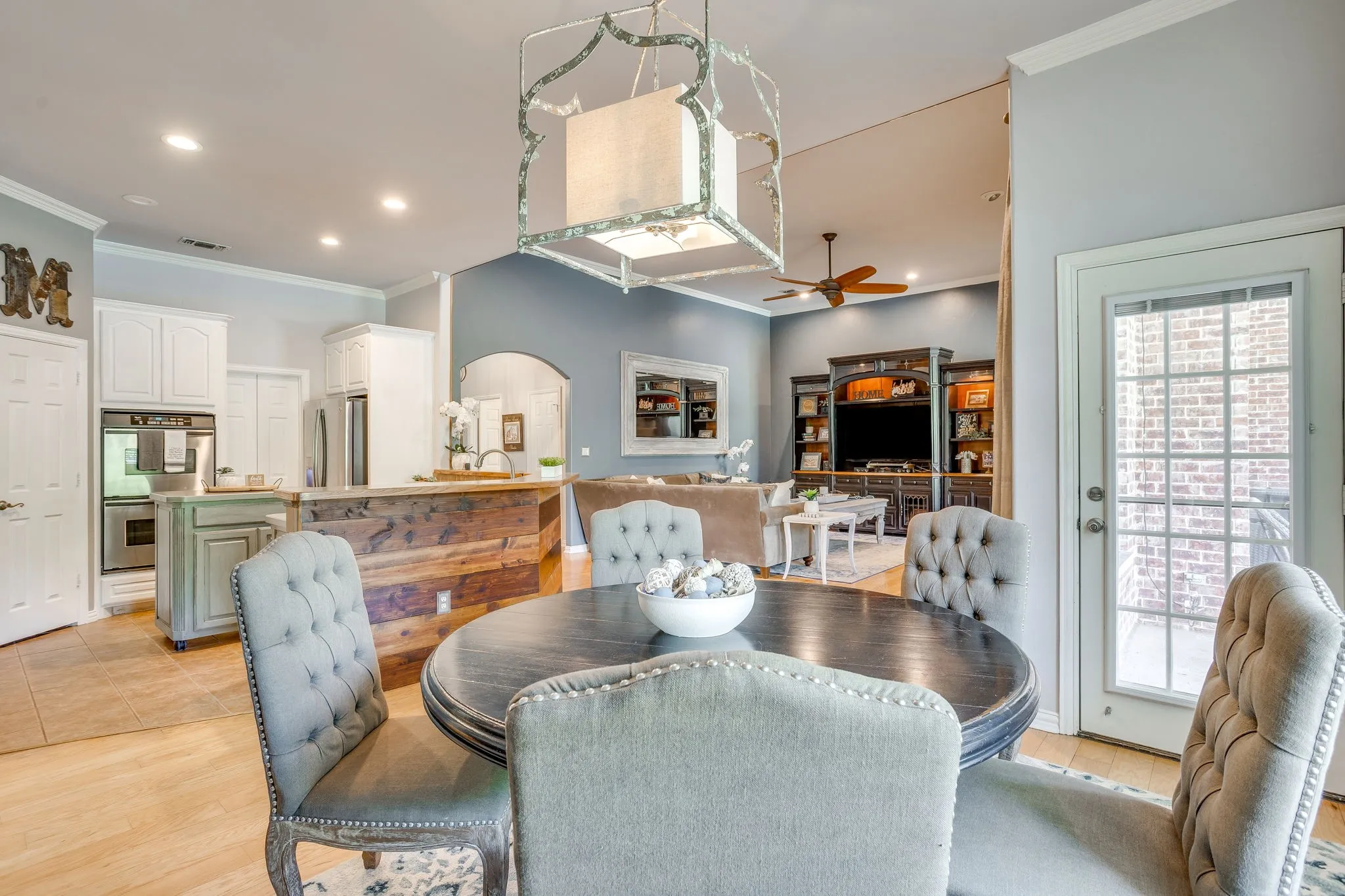 Open-concept living area with wood-finish flooring, a kitchen island with wood paneling, and built-in shelving