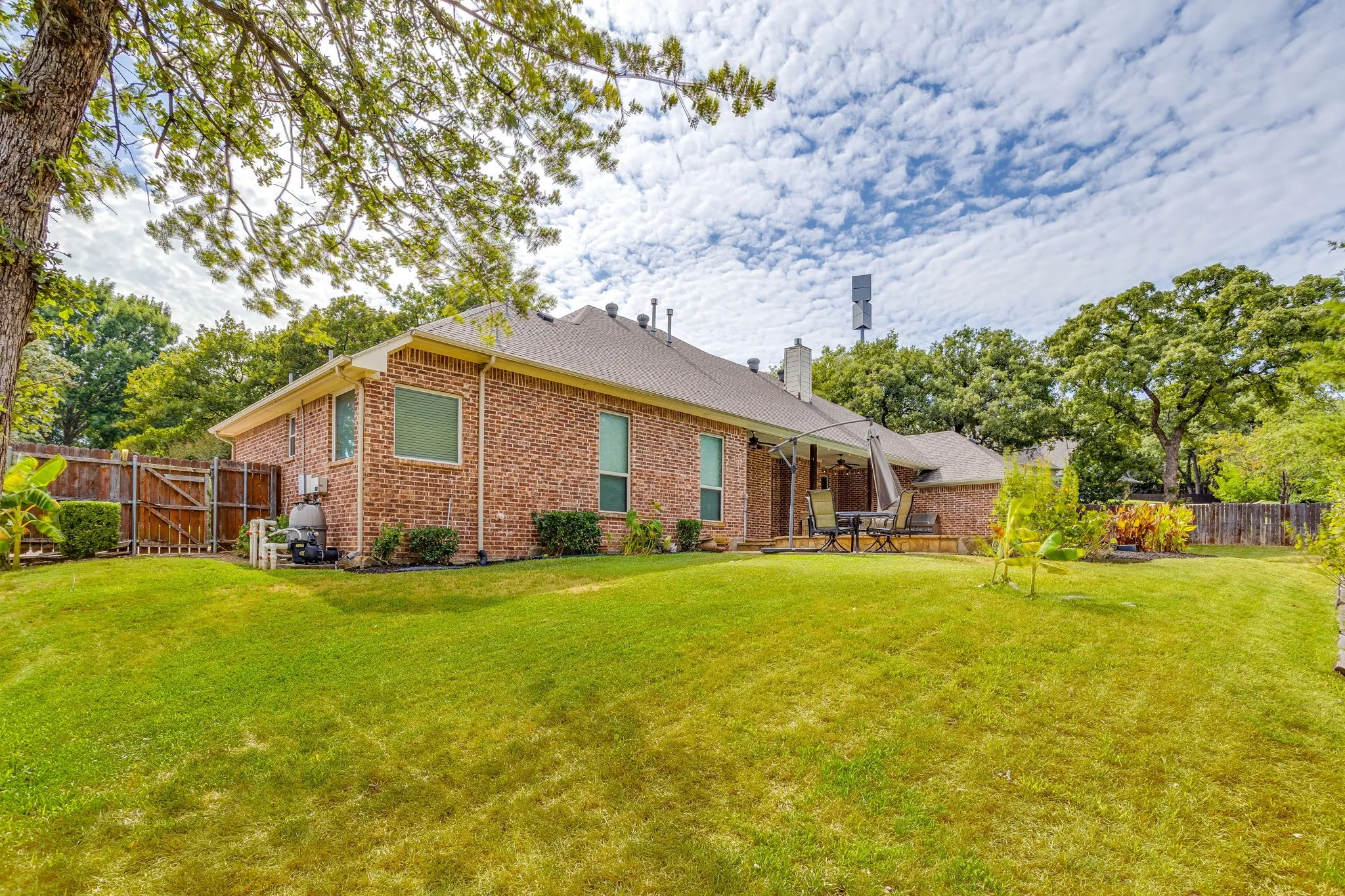 Expansive lawn with mature trees and a brick exterior