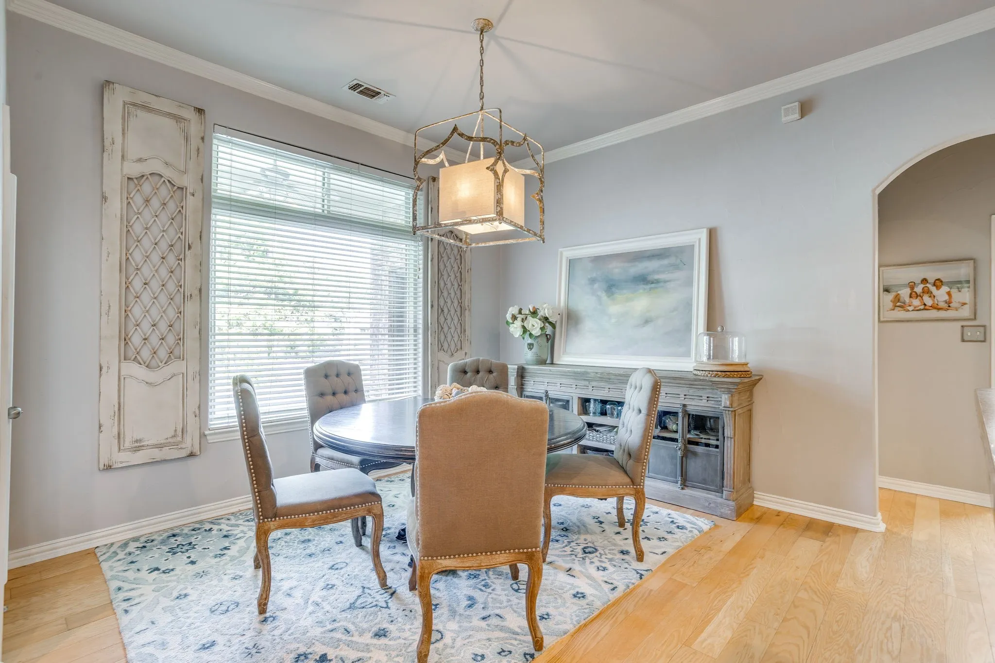 Dining area with wood-finish flooring, a large window with blinds, and crown molding