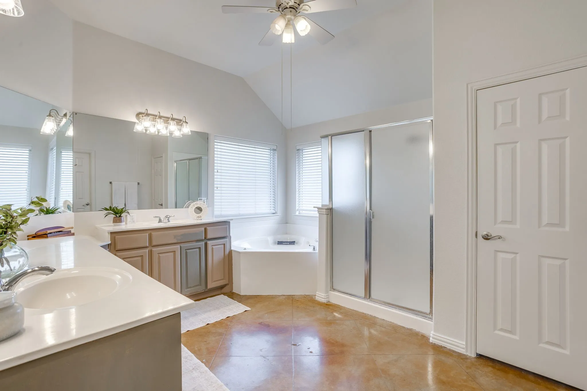 Dual vanity with under-mount sinks, large wall-mounted mirror, separate shower enclosure with frosted glass, and a corner soaking tub