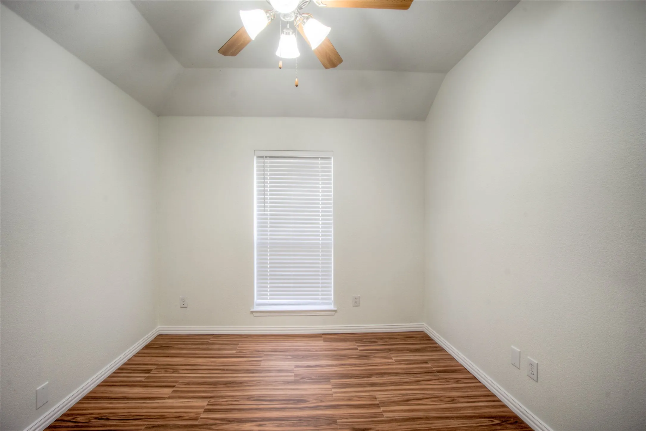 Vaulted ceiling with a ceiling fan, a window with horizontal blinds, wood-finish flooring, and white trim