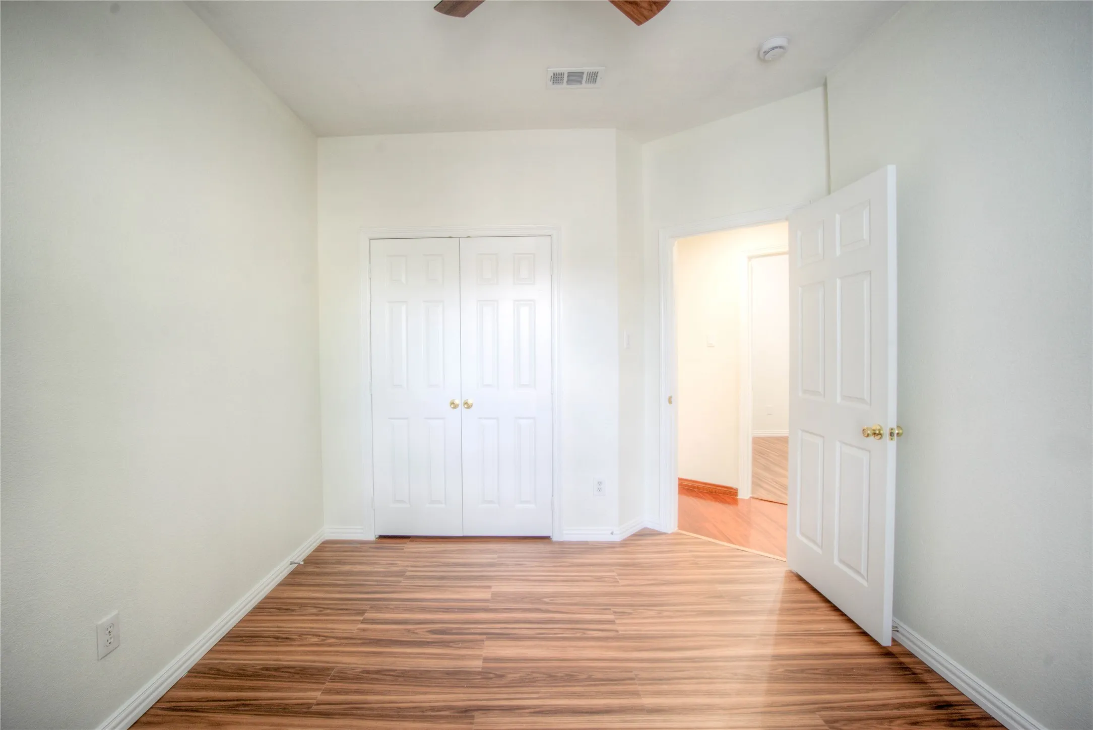 Wood-finish flooring, white walls, and a ceiling fan