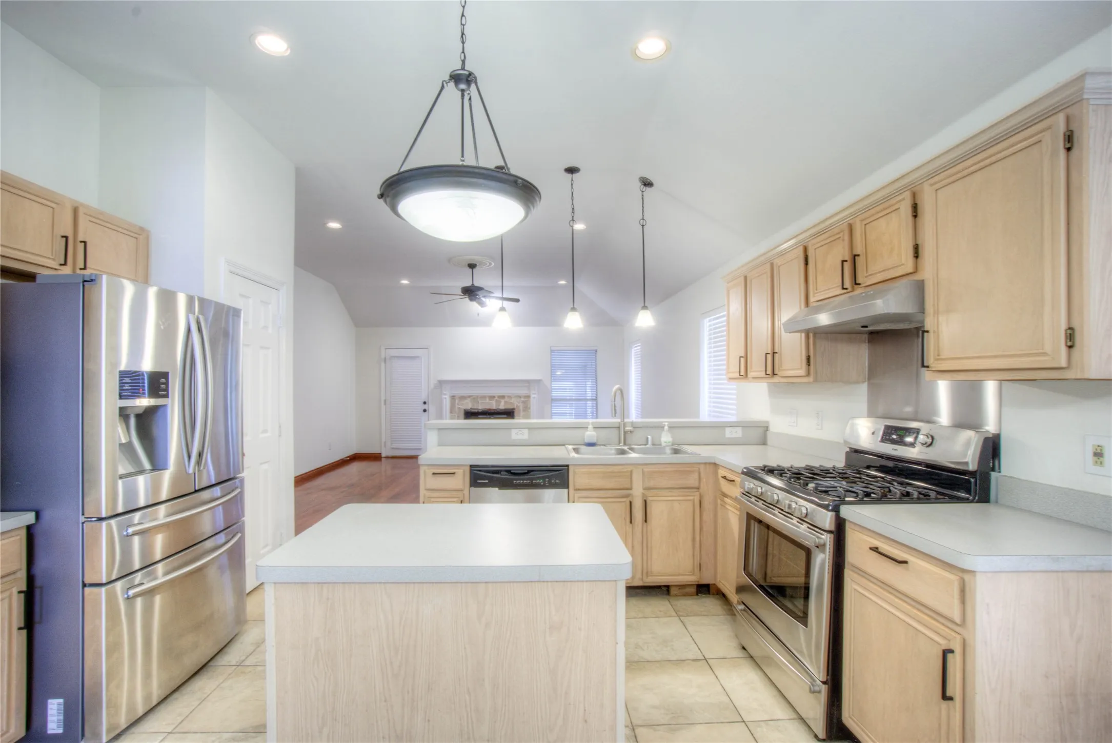 Kitchen featuring stainless steel appliances, light wood-finish cabinetry, a central island, recessed lighting, and tile flooring