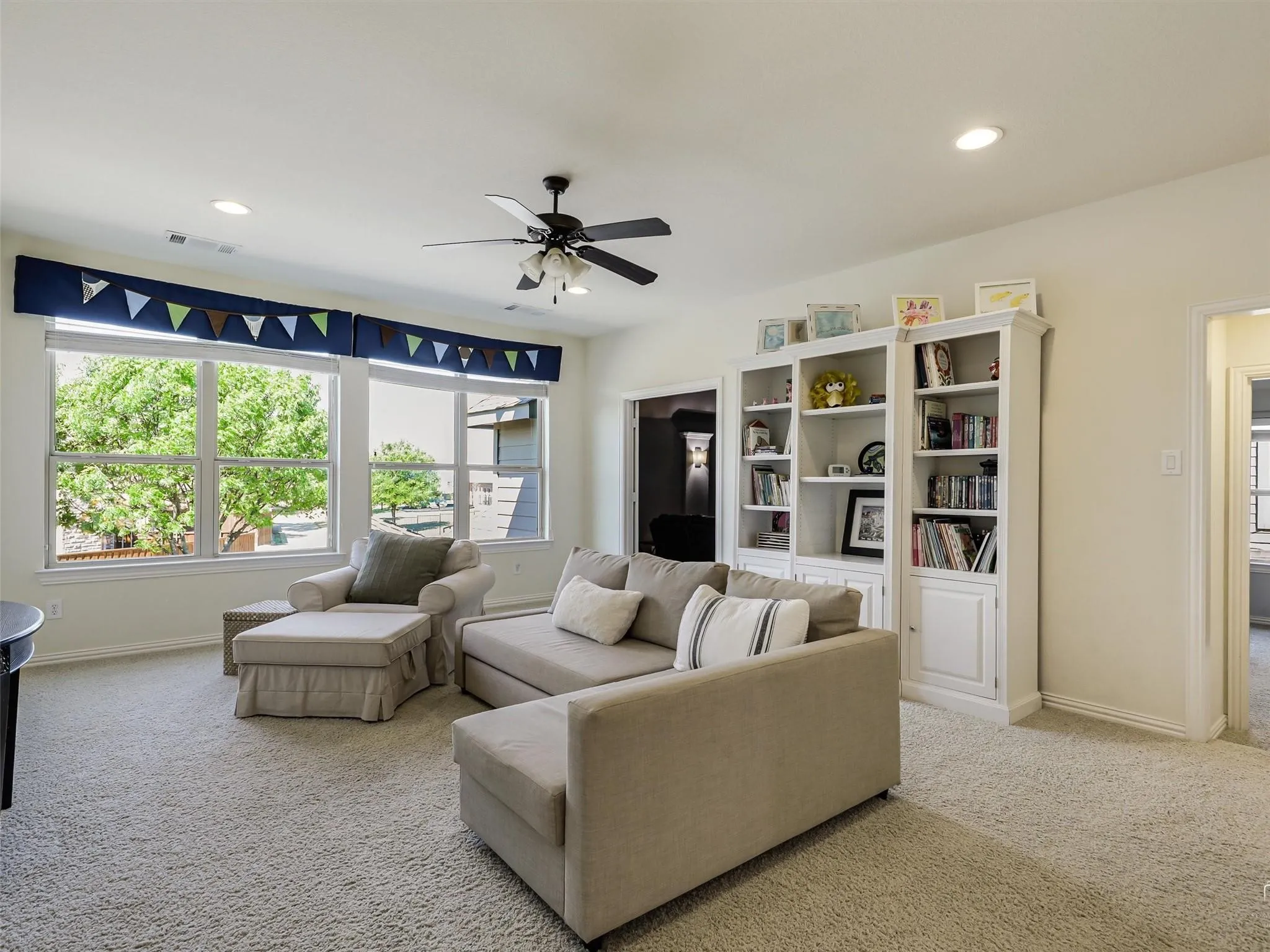 Recessed ceiling lighting, a ceiling fan, and built-in white shelving units