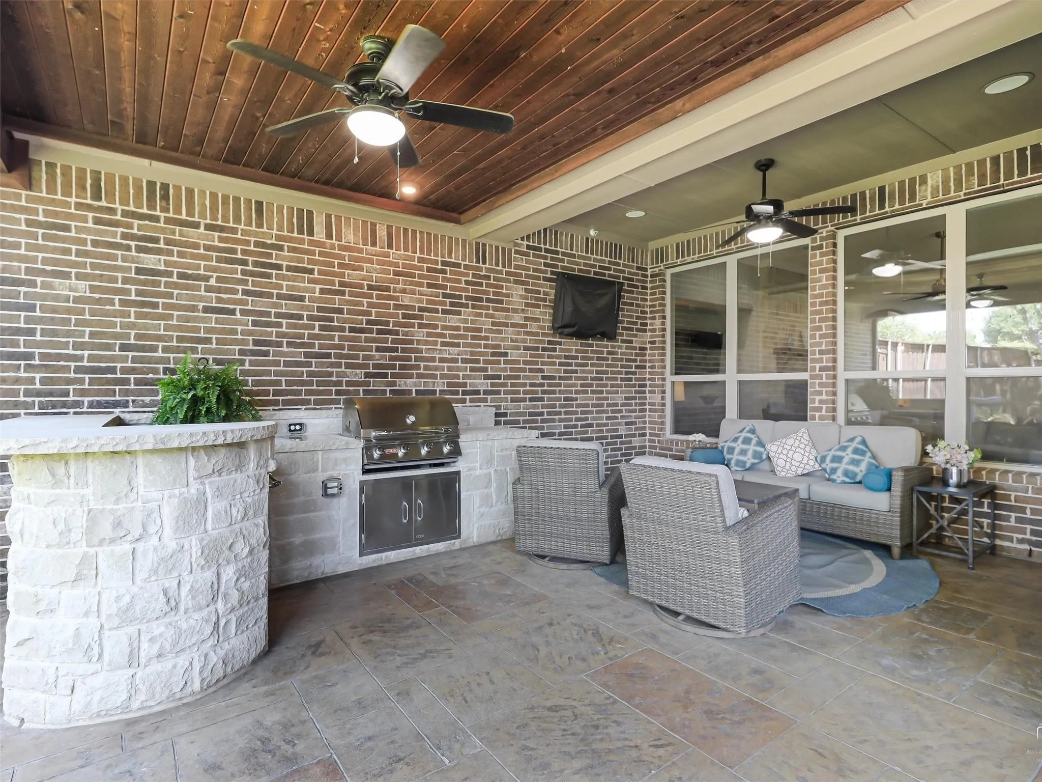 Covered patio featuring a wood-plank ceiling, brick walls, and stamped concrete flooring