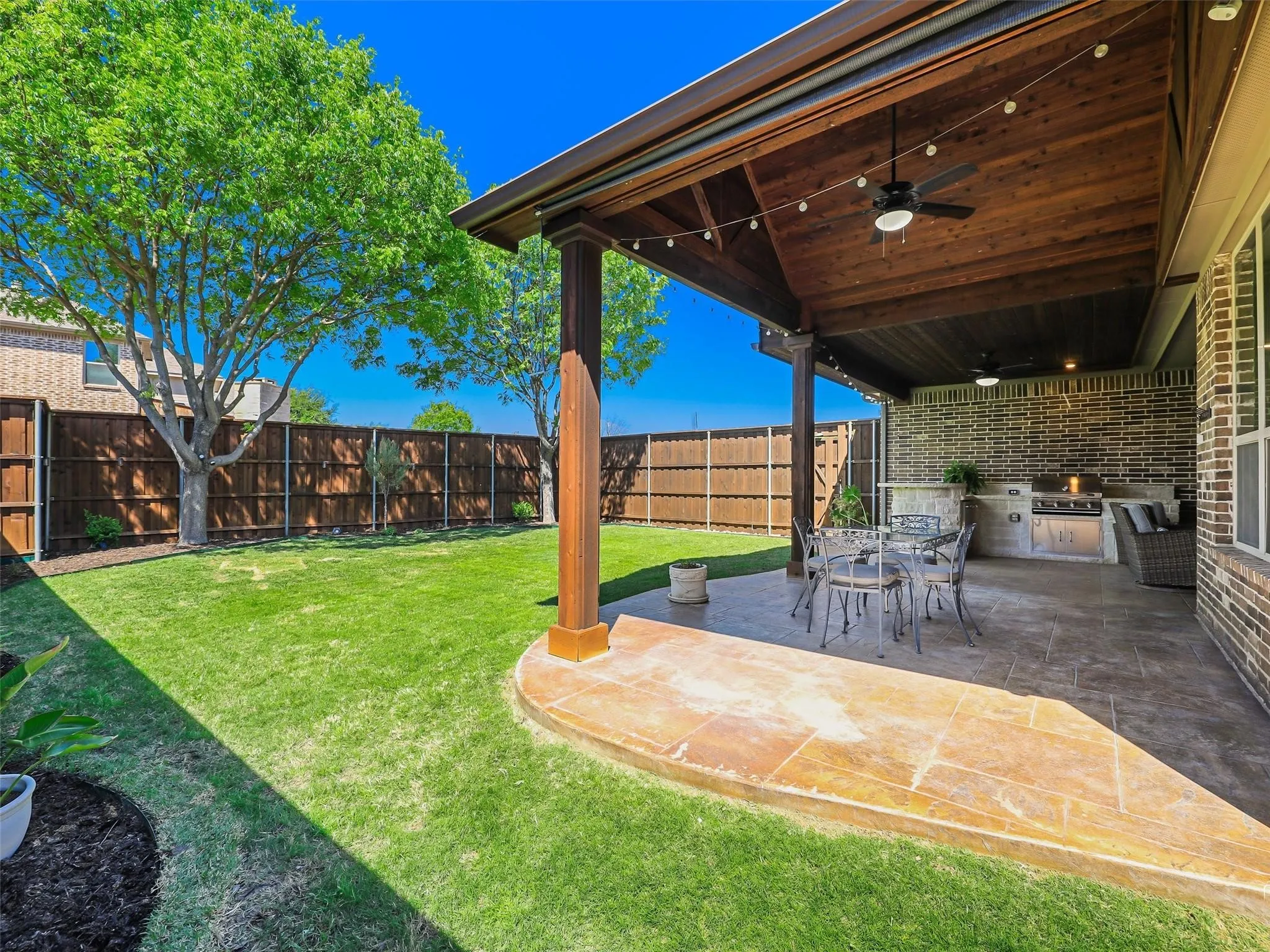 Covered patio with a wood-plank ceiling, built-in outdoor kitchen, and ceiling fans