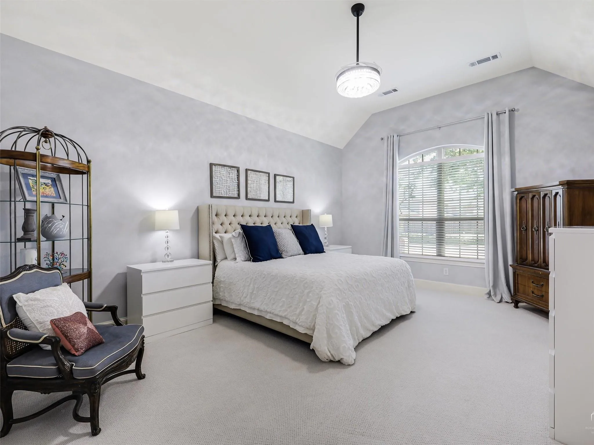 Vaulted ceiling, arched window, wall-to-wall carpeting, and a tufted upholstered headboard