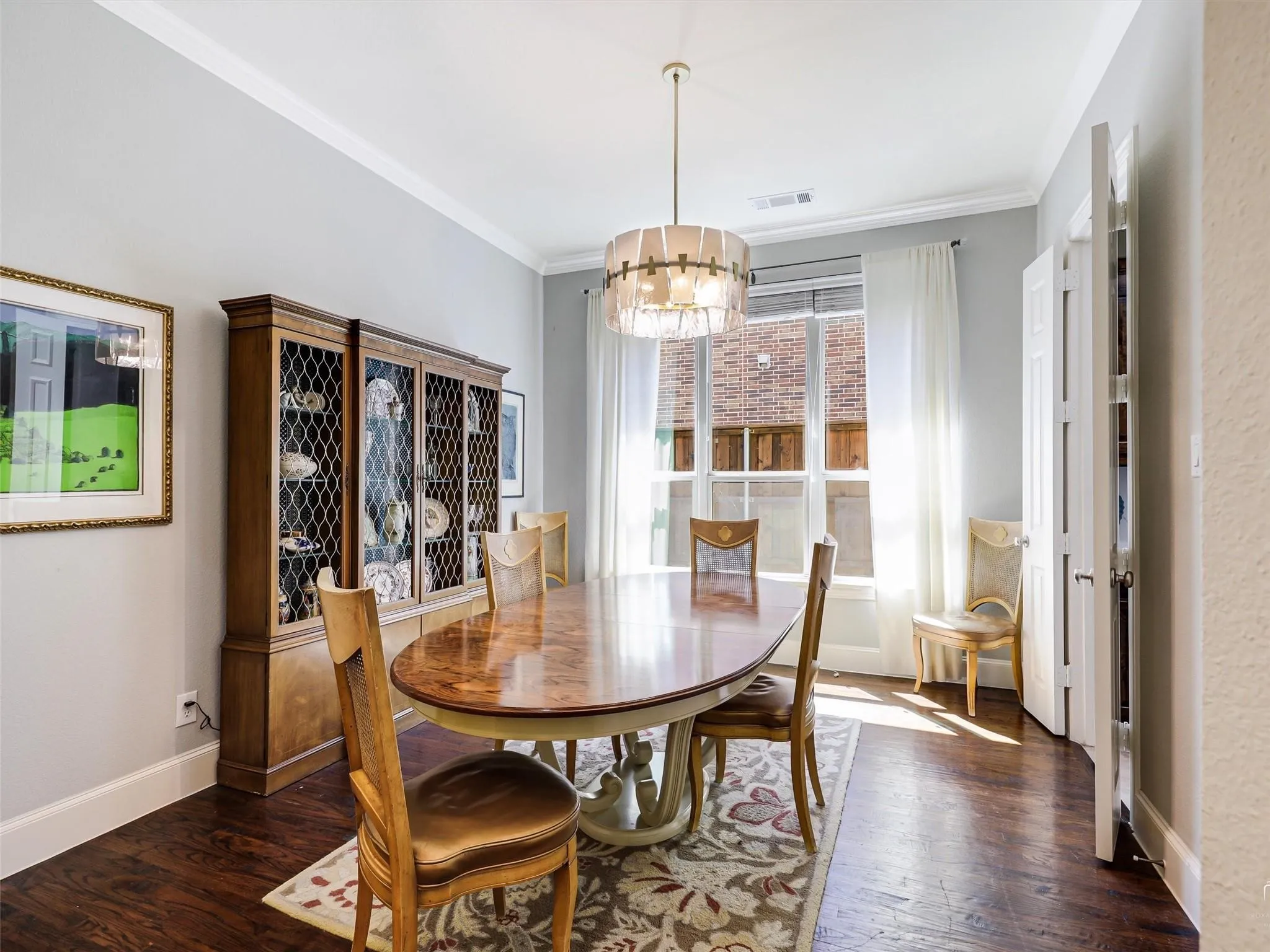 Wood-finish flooring, crown molding, white trim, and a contemporary chandelier