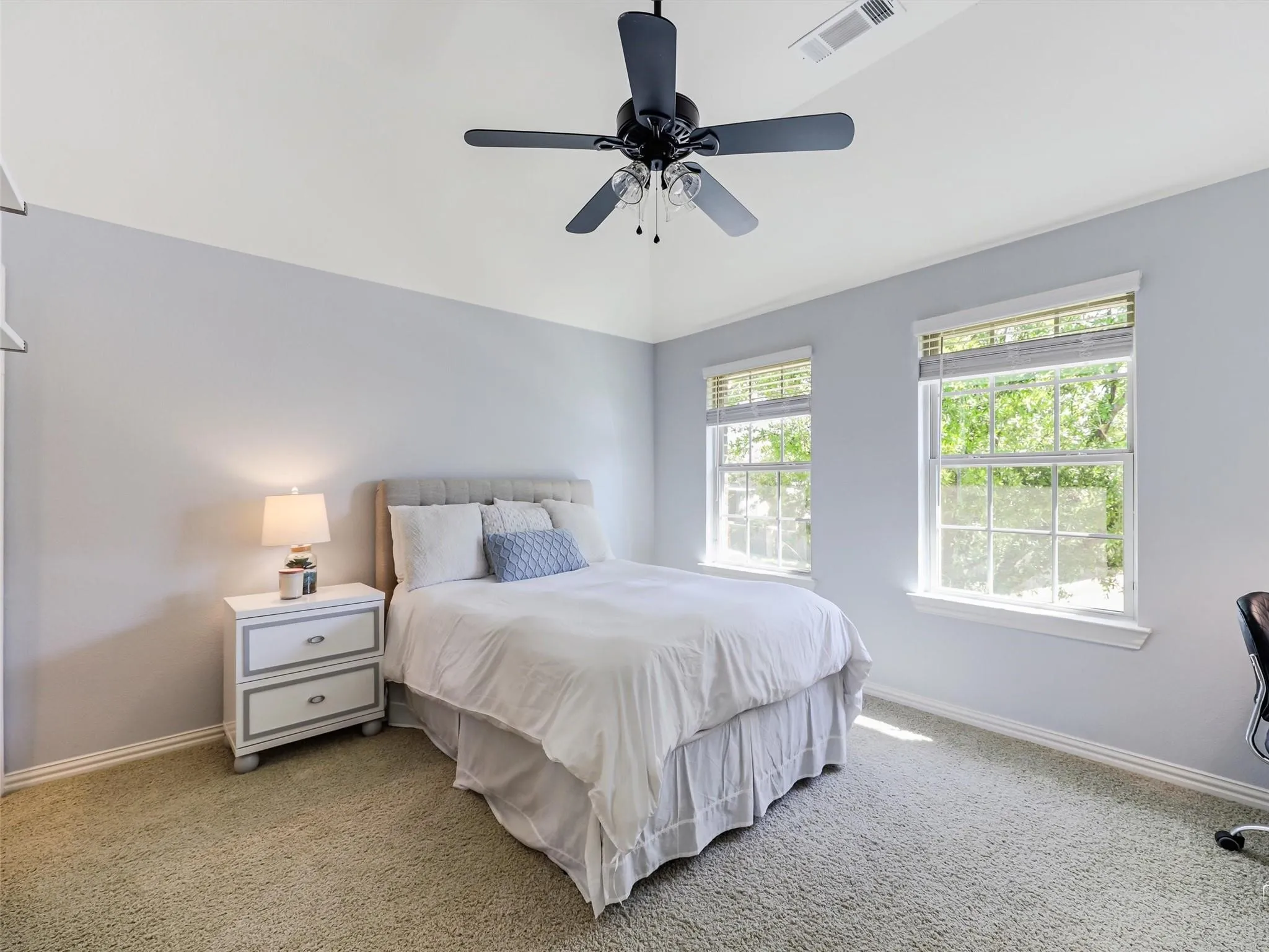 Vaulted ceiling with a ceiling fan, two windows with blinds, and light-colored wall paint