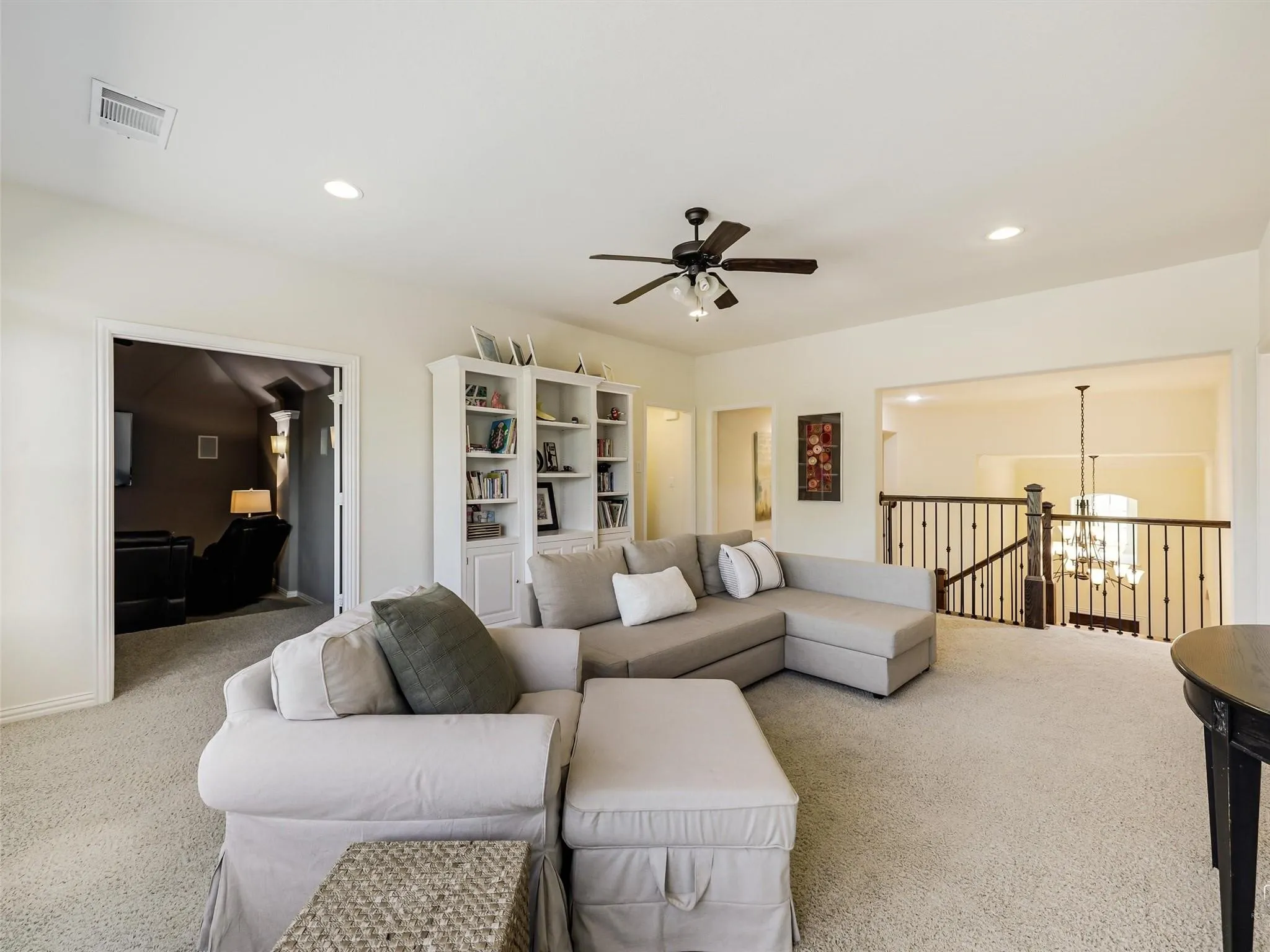 Recessed lighting, ceiling fan, built-in shelving, open stairwell with metal balusters, and a carpeted floor