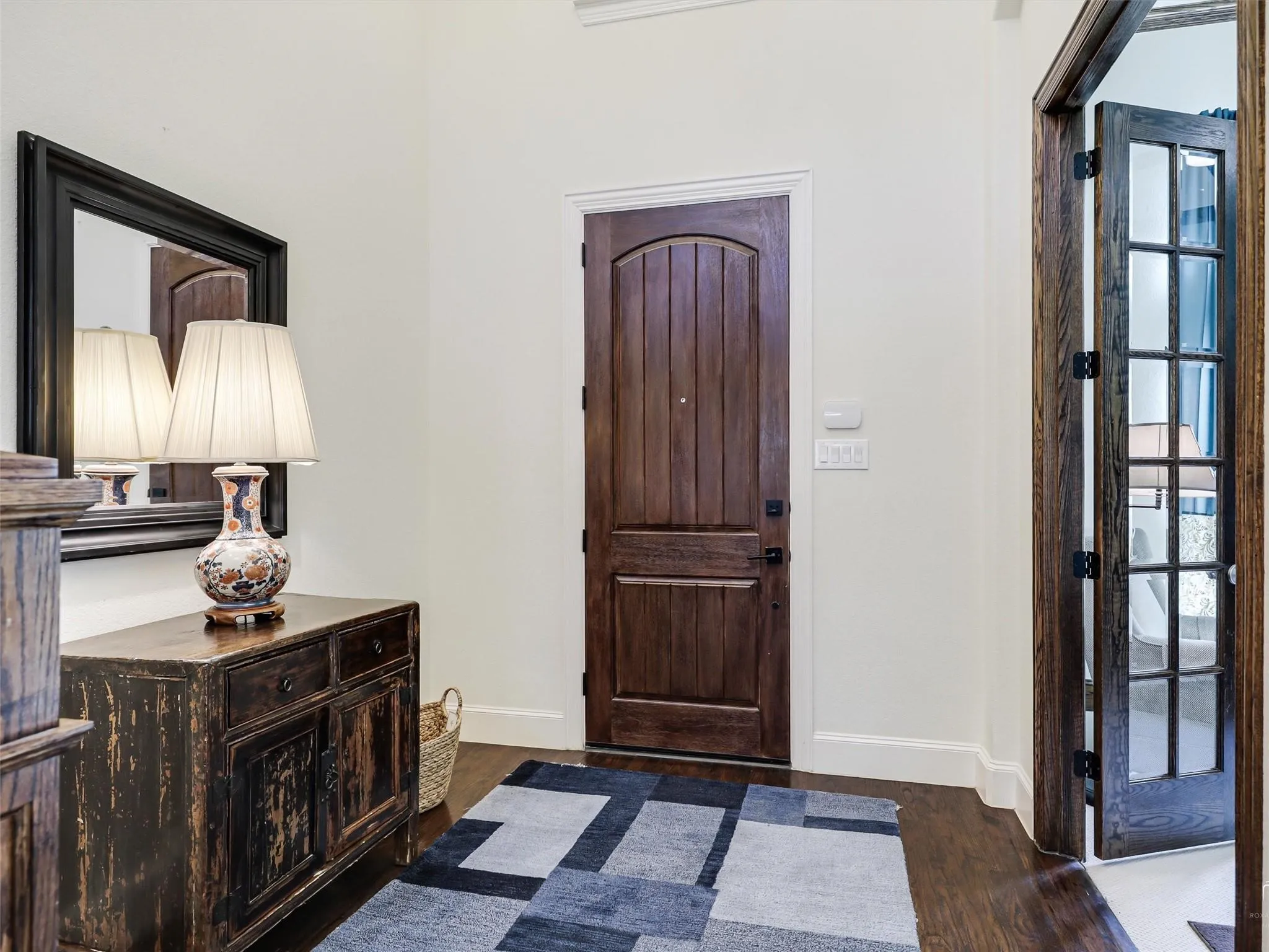 Rich wood-finish flooring, solid wood entry door, and French paneled interior door