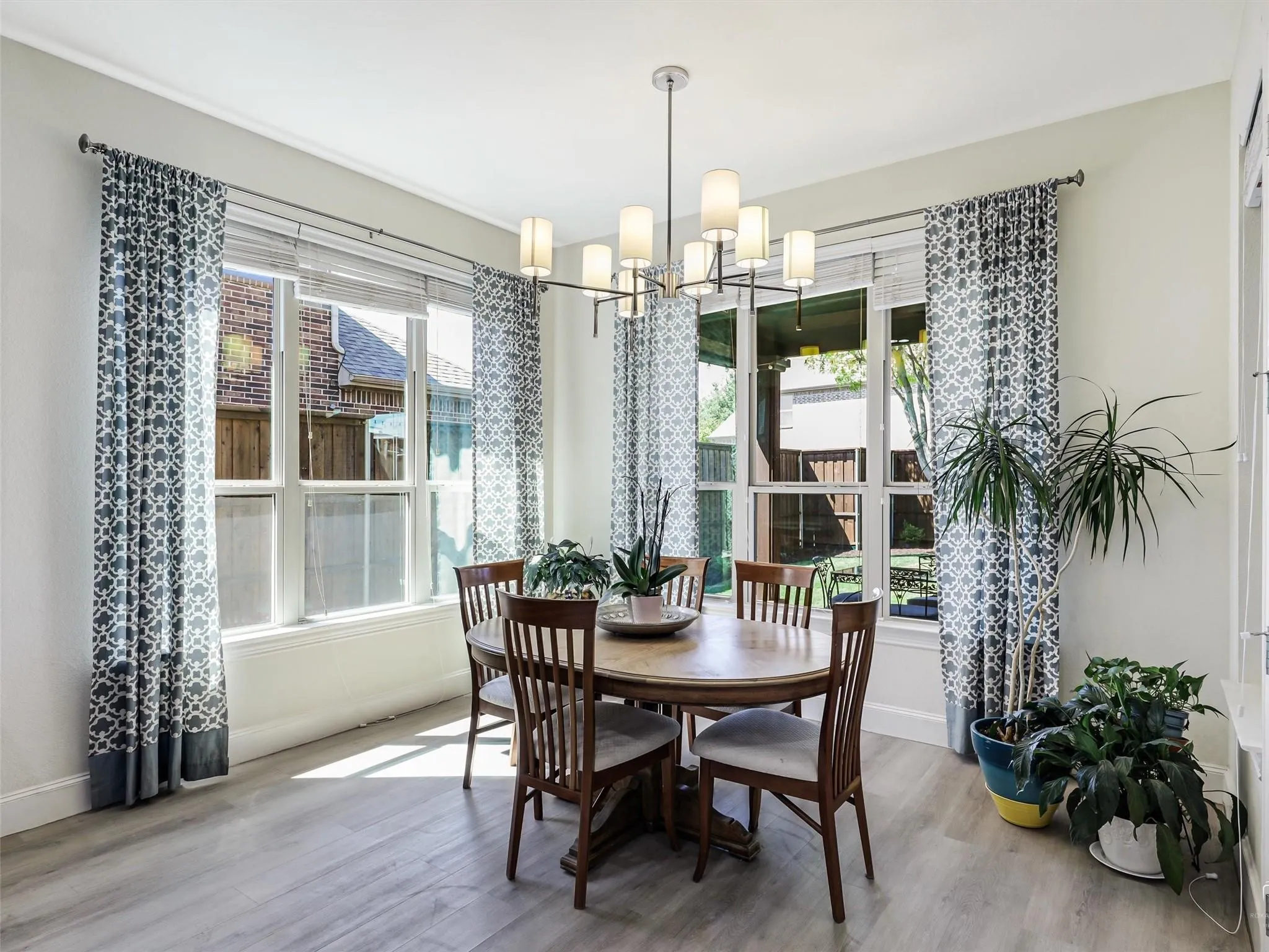 Laminate wood-look flooring, multiple large windows, and a multi-arm linear chandelier