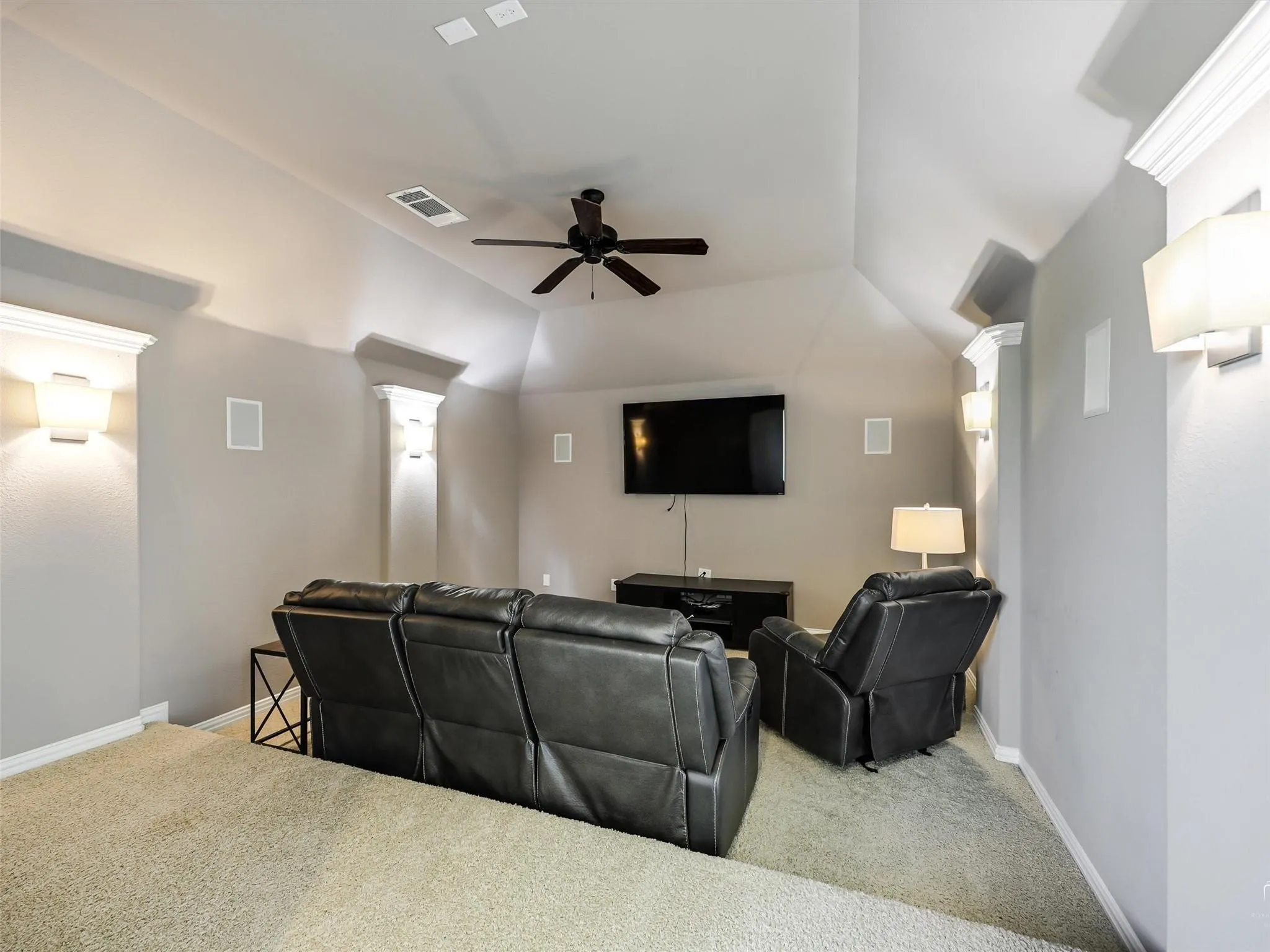 Vaulted ceiling, recessed lighting, built-in wall speakers, wall-mounted sconces, and a ceiling fan