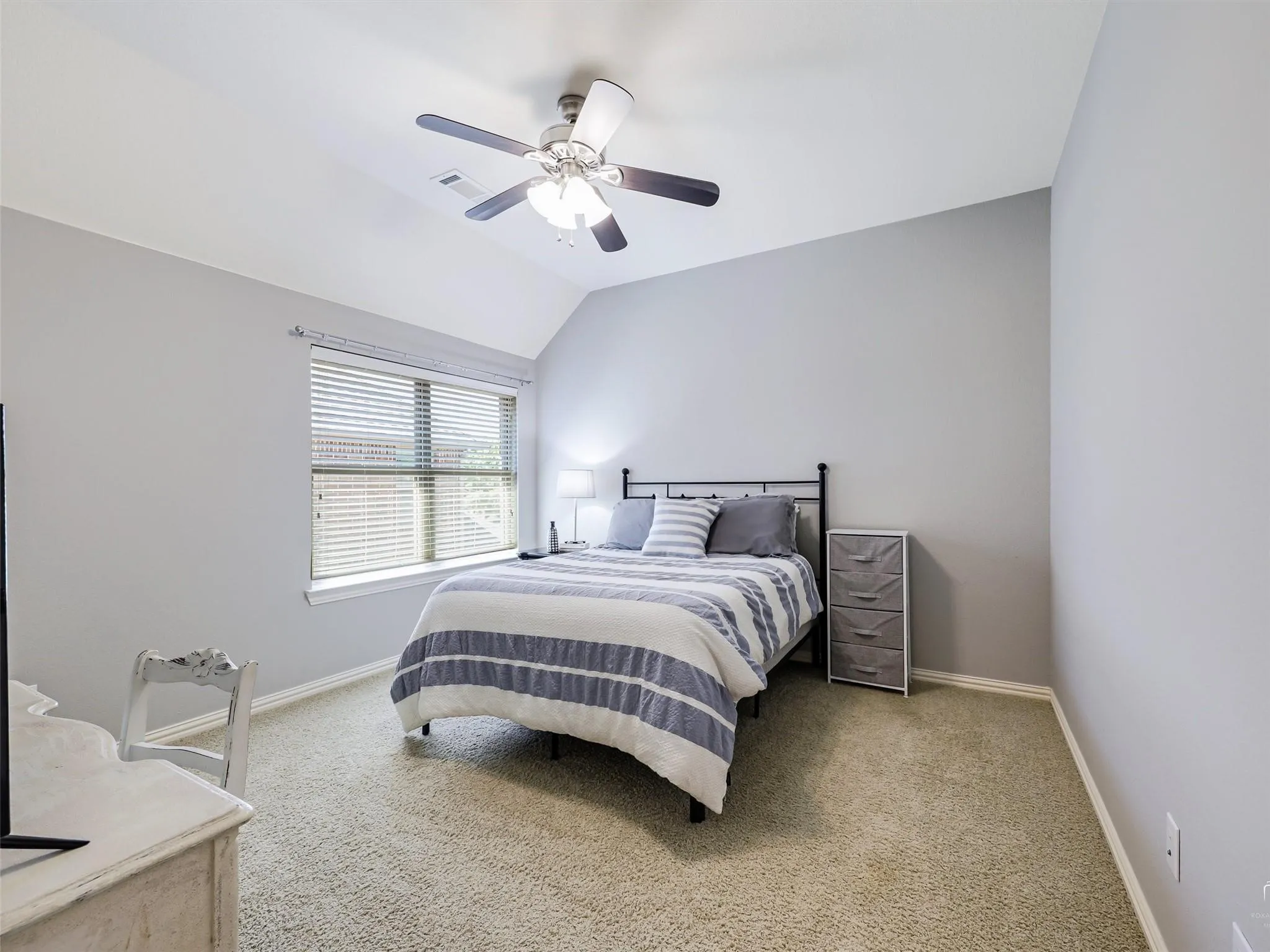 Carpeted room featuring a vaulted ceiling with a ceiling fan, window with blinds, and light gray wall paint
