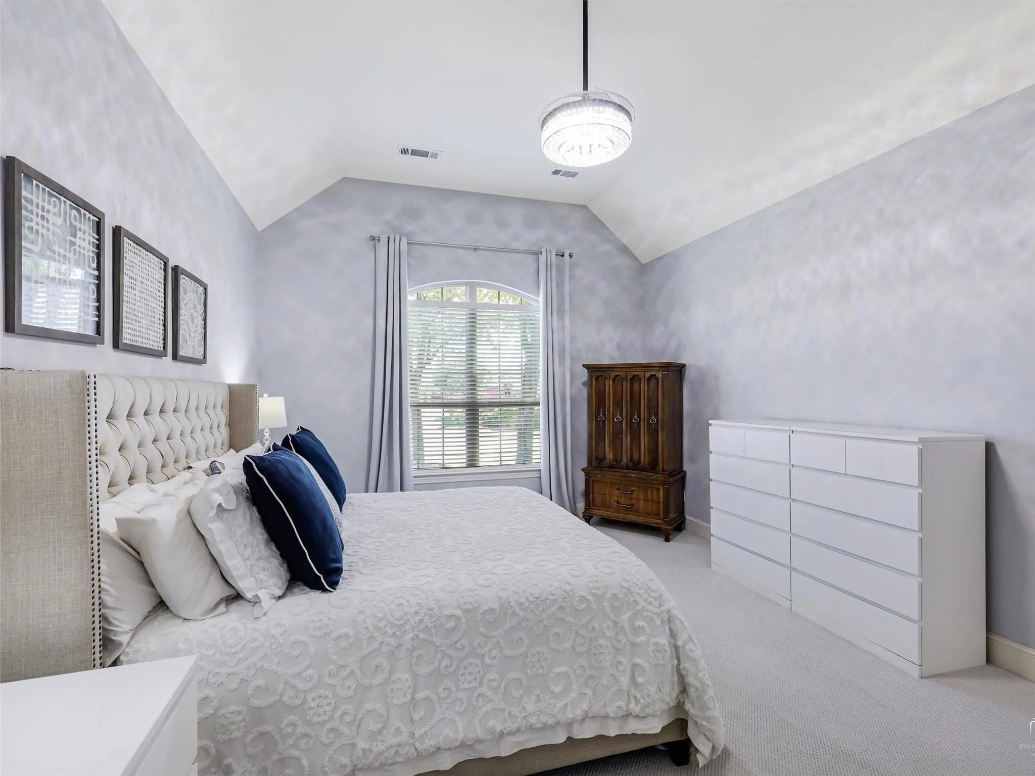 Vaulted ceiling with an attached light fixture, light gray carpeting, and an arched window