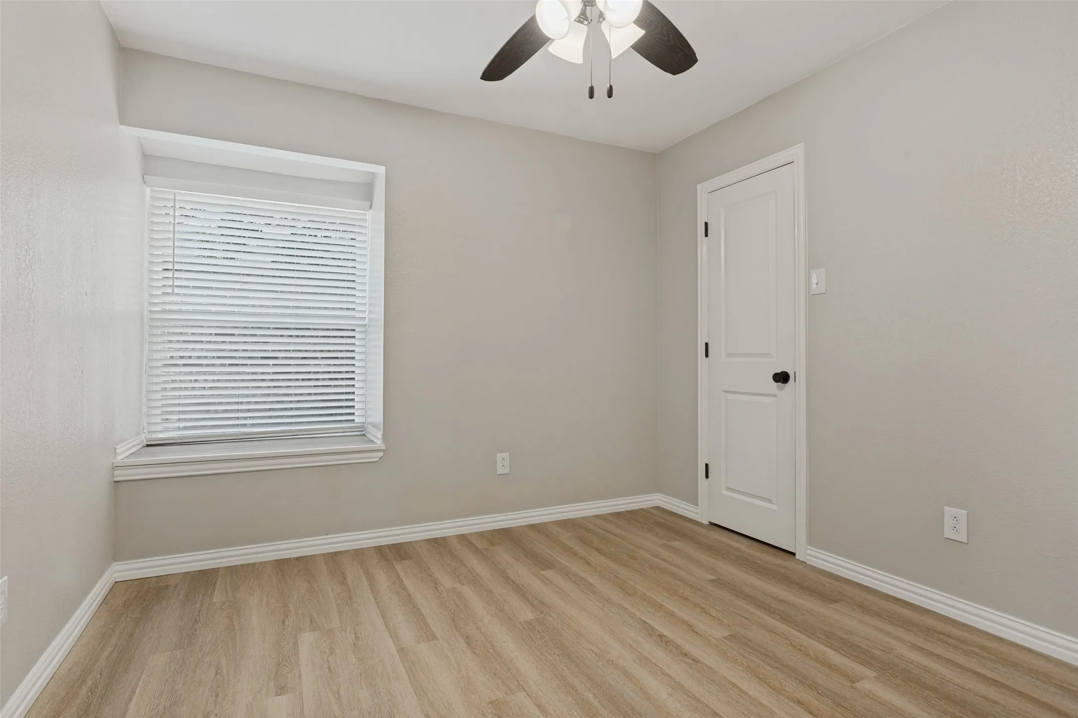 Secondary bedroom featuring luxury vinyl plank flooring, a ceiling fan, window seat area with blinds, and white trim.