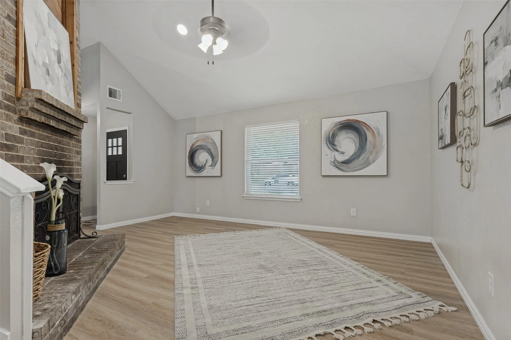 View shows the vaulted ceiling, window views to front yard, lighted ceiling fan, recessed art lighting for fireplace.