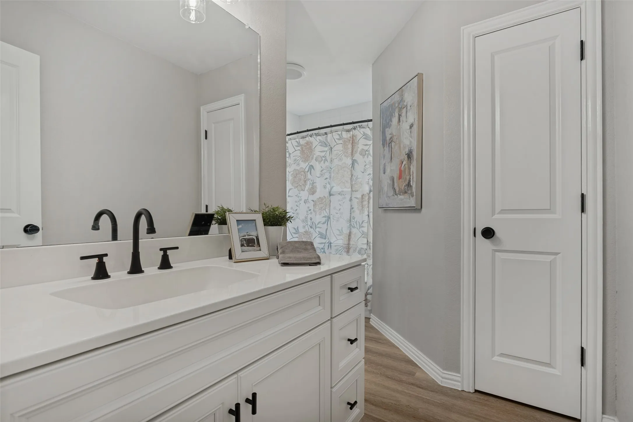 Secondary bath with white vanity, integrated rectangular sink and matte black fixtures.