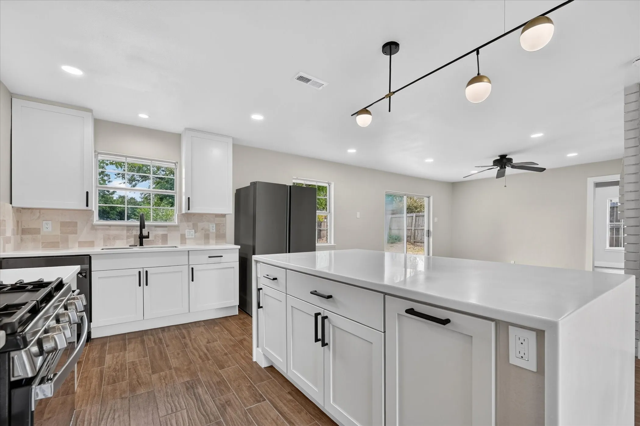 White shaker cabinetry, light-toned backsplash, and a central island with a white countertop