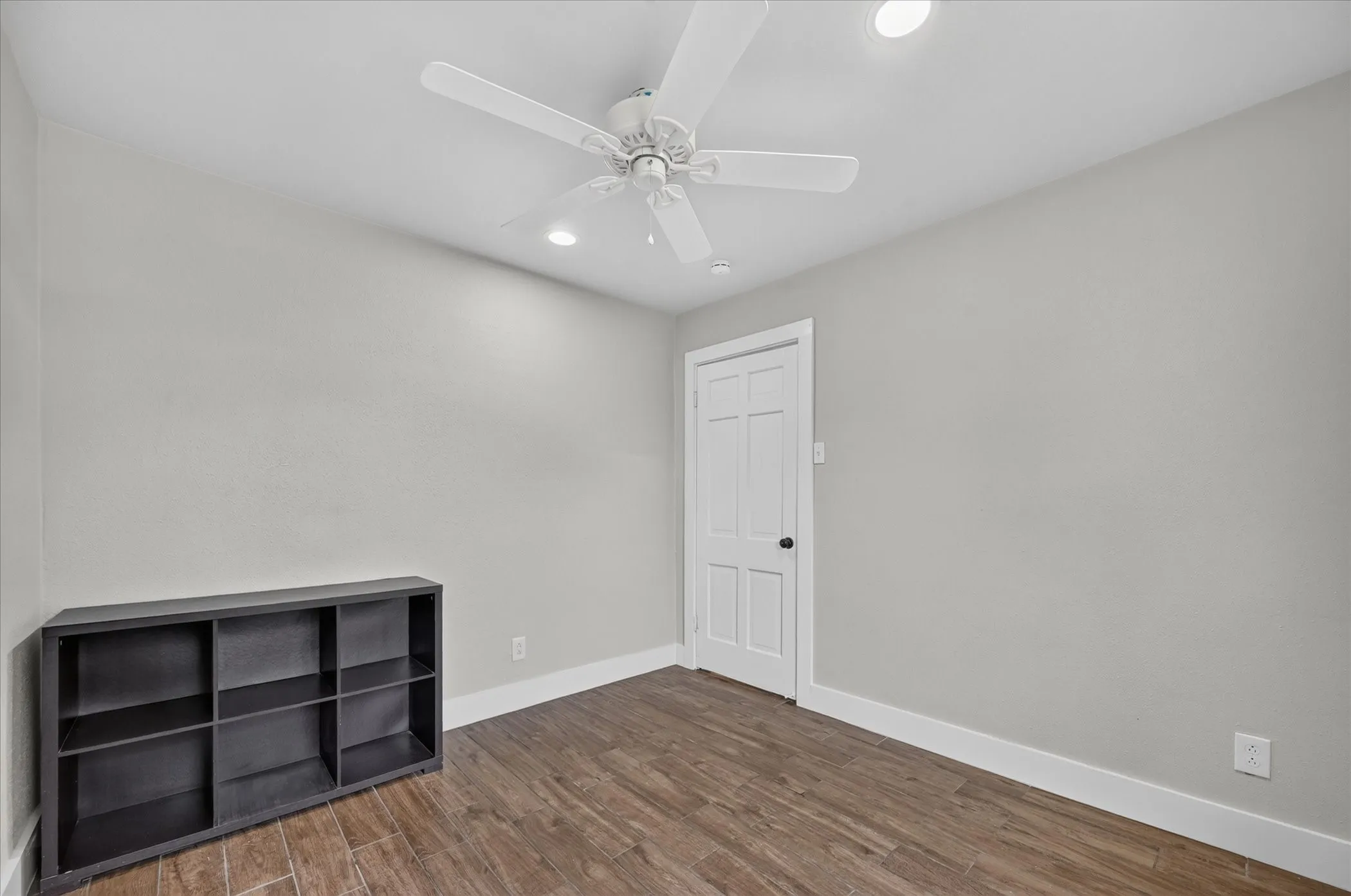 Wood-finish flooring with white trim, recessed lighting, and a ceiling fan