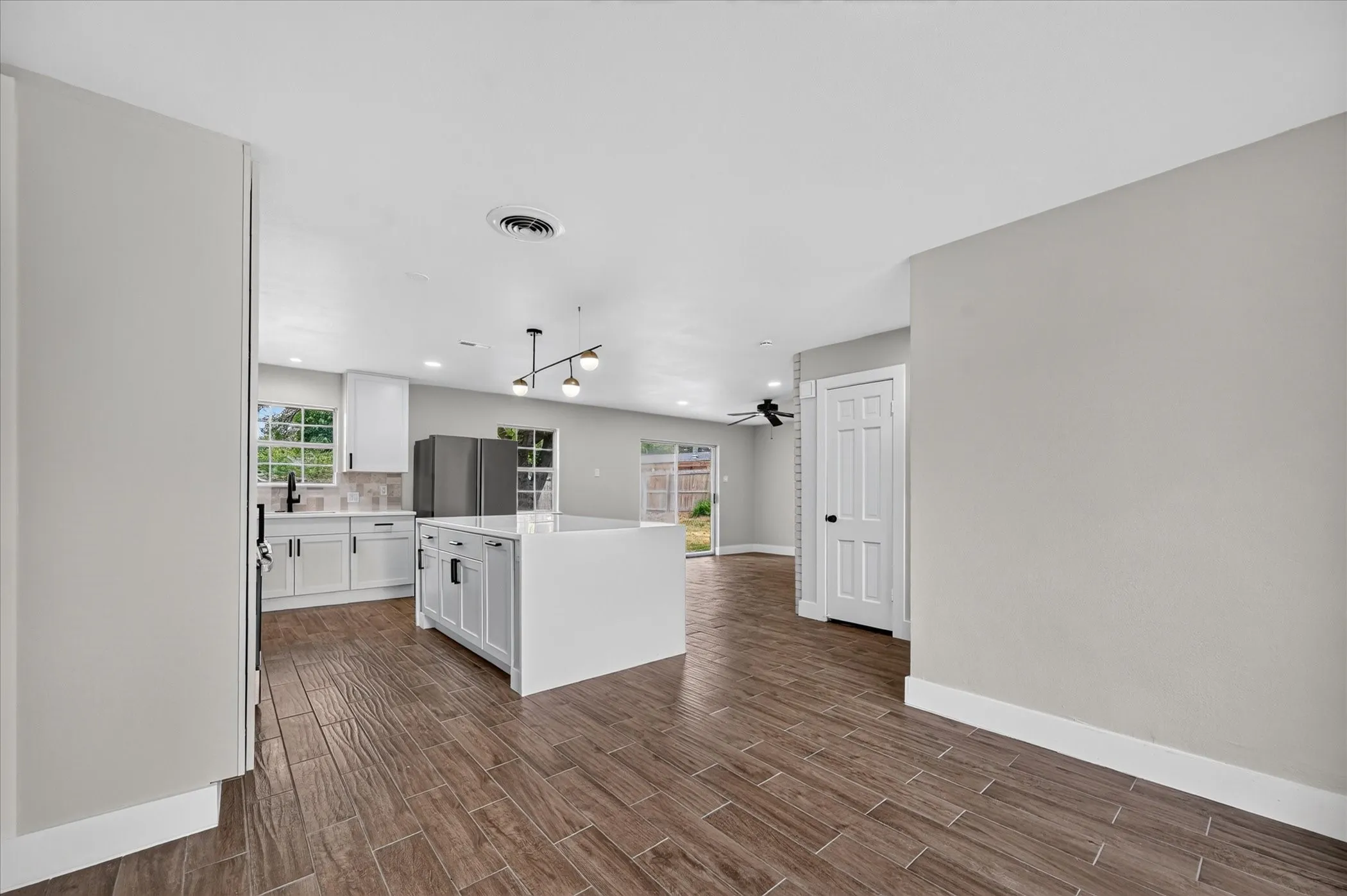 Spacious kitchen with white cabinetry, a large island, stainless steel appliances, and wood-finish flooring