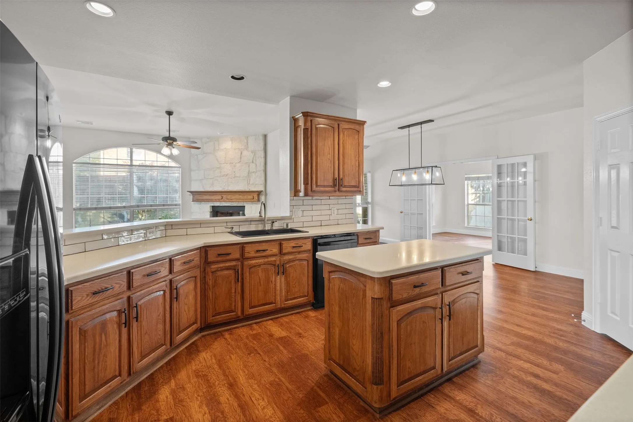 Kitchen with wood-finish flooring, wood cabinetry, light countertops, and a subway tile backsplash